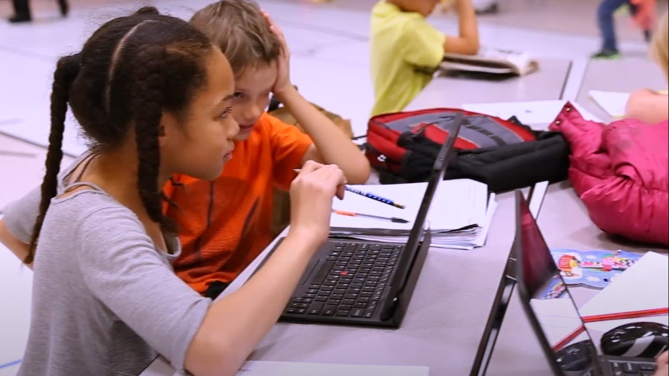 two students looking at a laptop screen