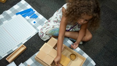 stludent sitting on floor doing montessori activities