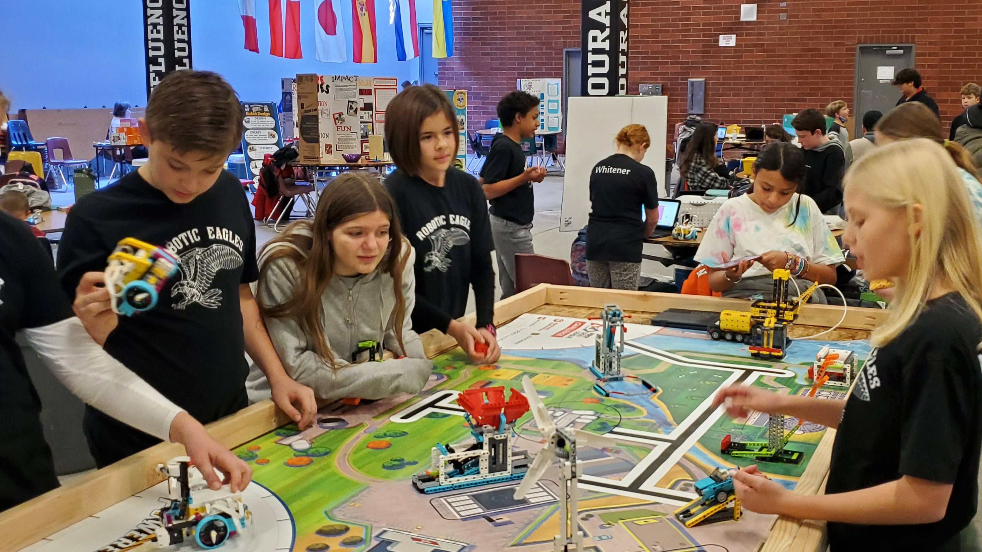 five students standing around a sim town table