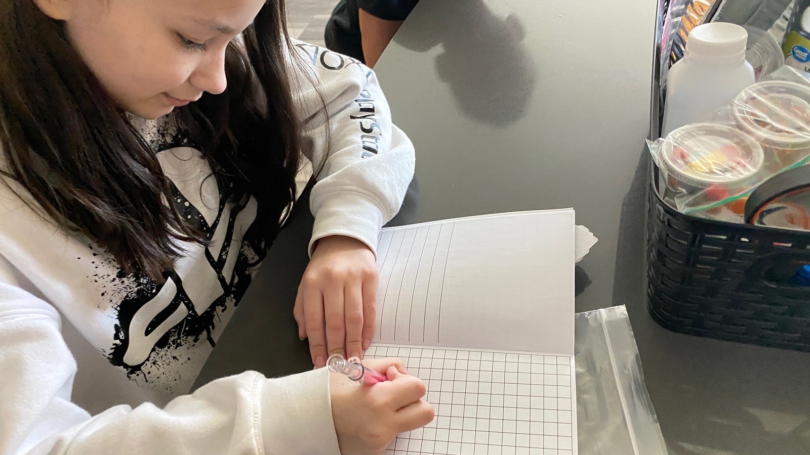 student writing in a notebook with graph paper