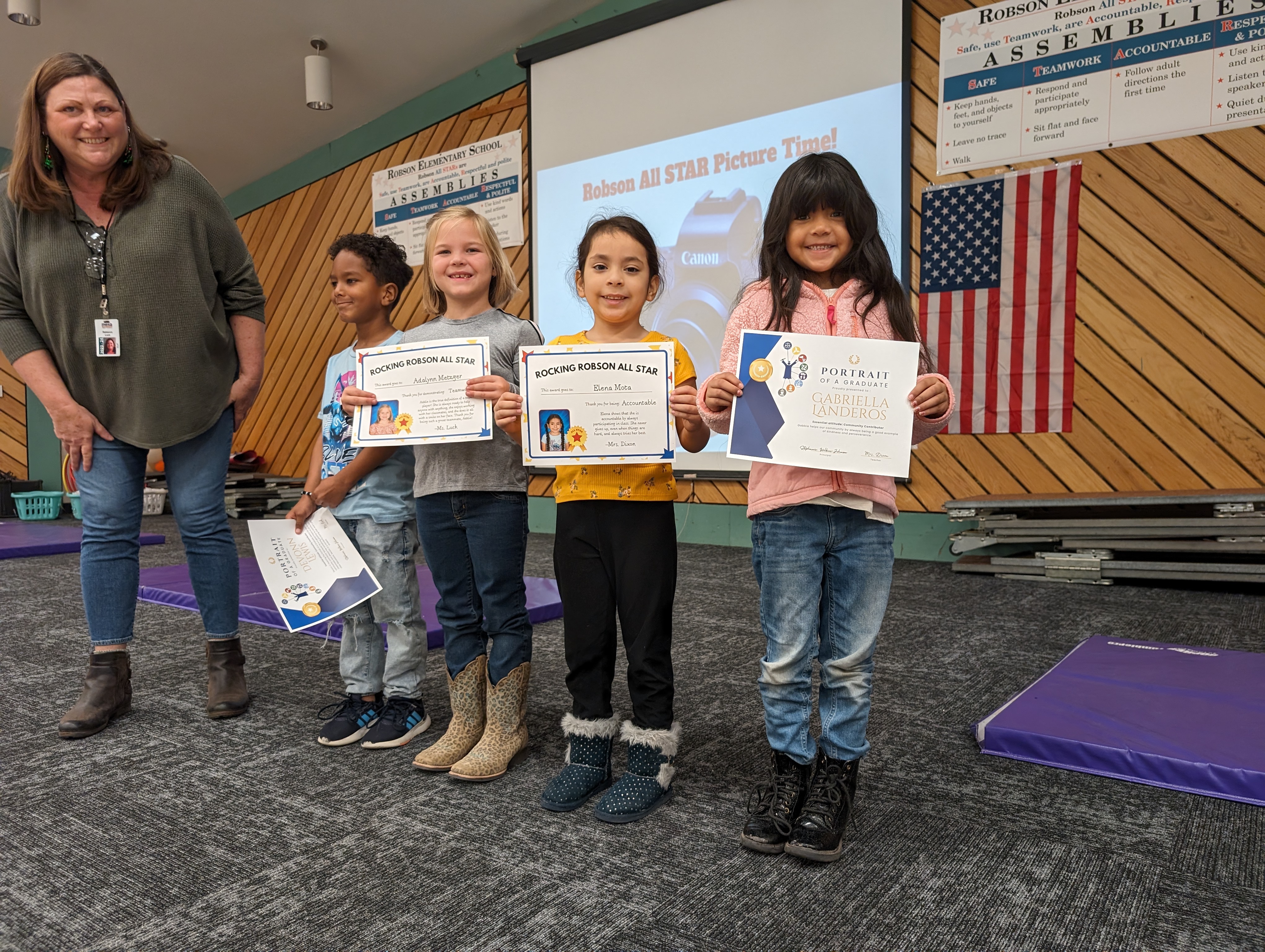 Four first graders and a teacher lined up on stage, after receiving awards.