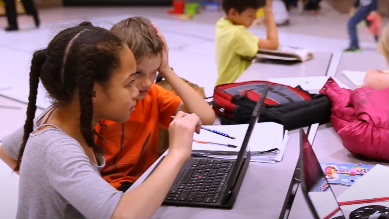 two students looking at a laptop screen