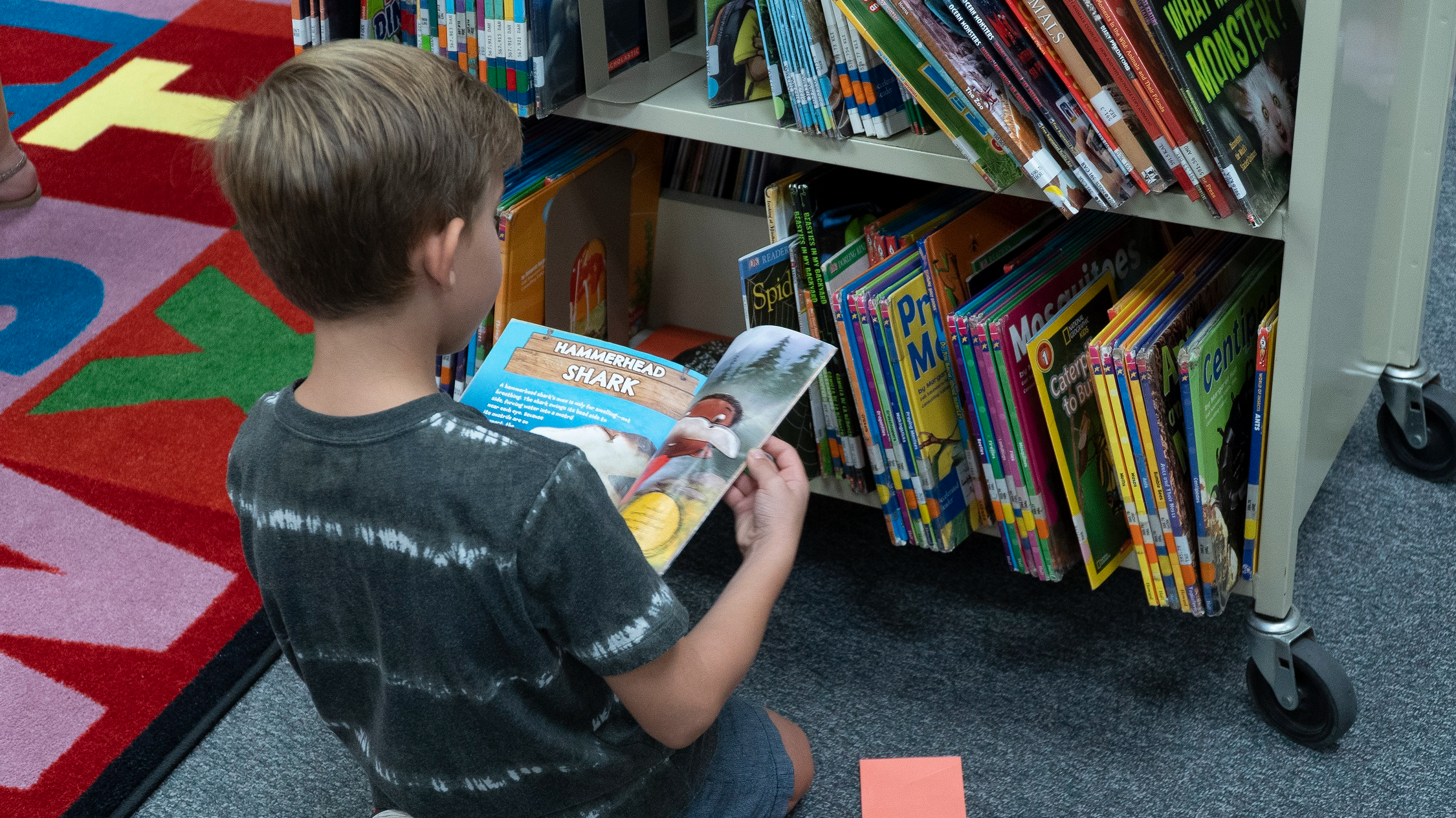 student stting on the floor looking at a cart of books