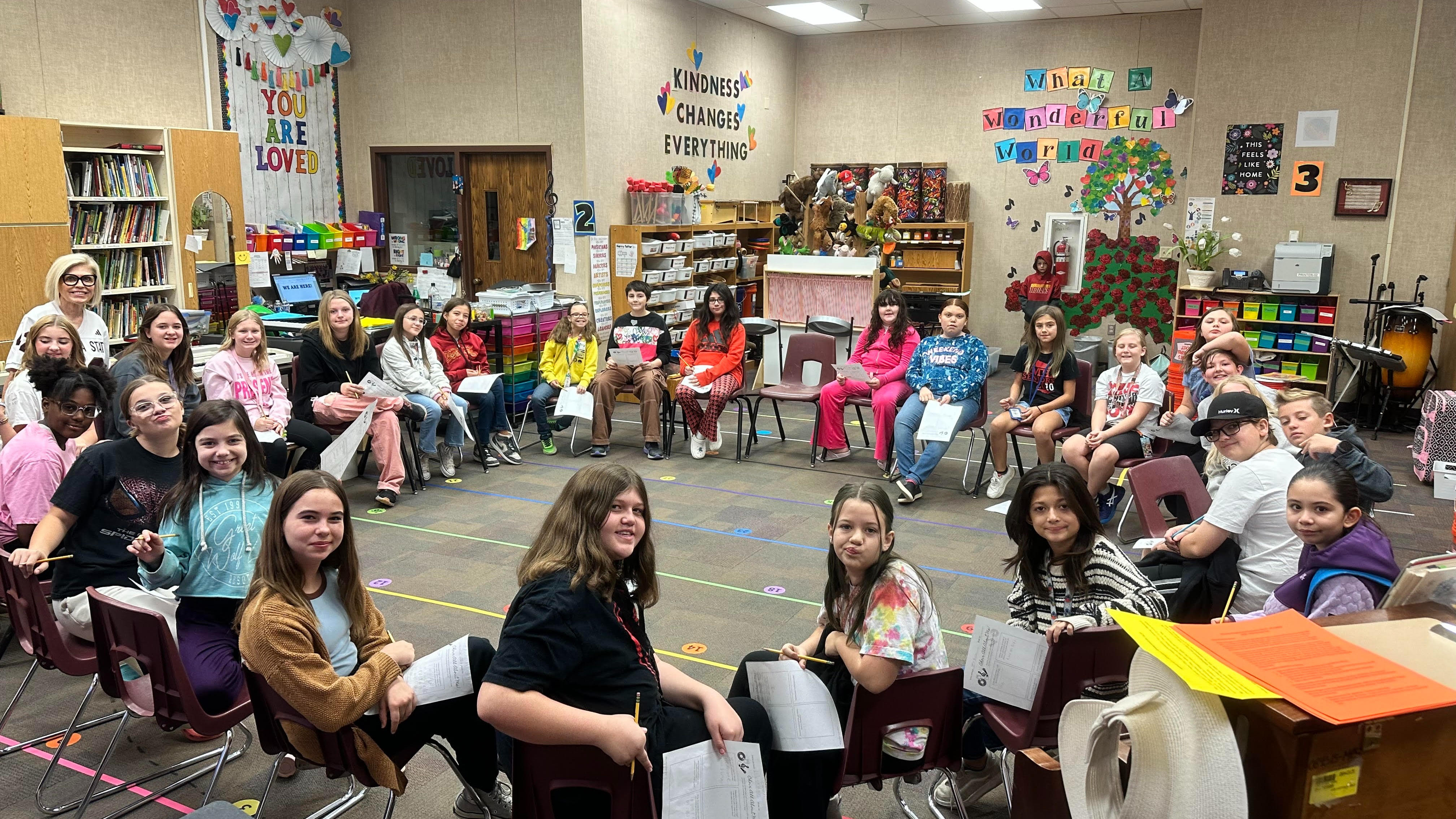 students sitting in chairs in a circle around a classroom