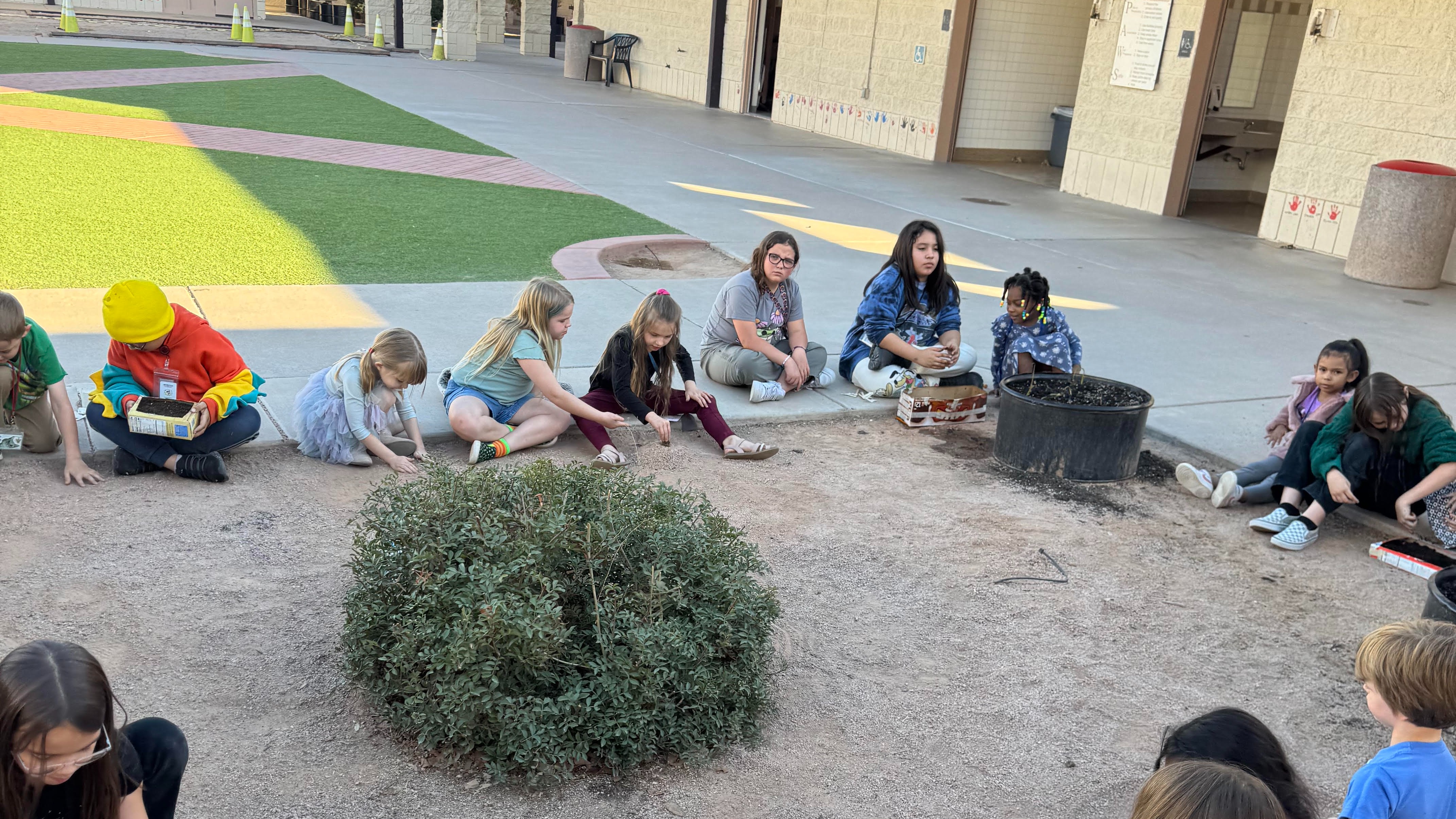 students sitting in a circle around a garden