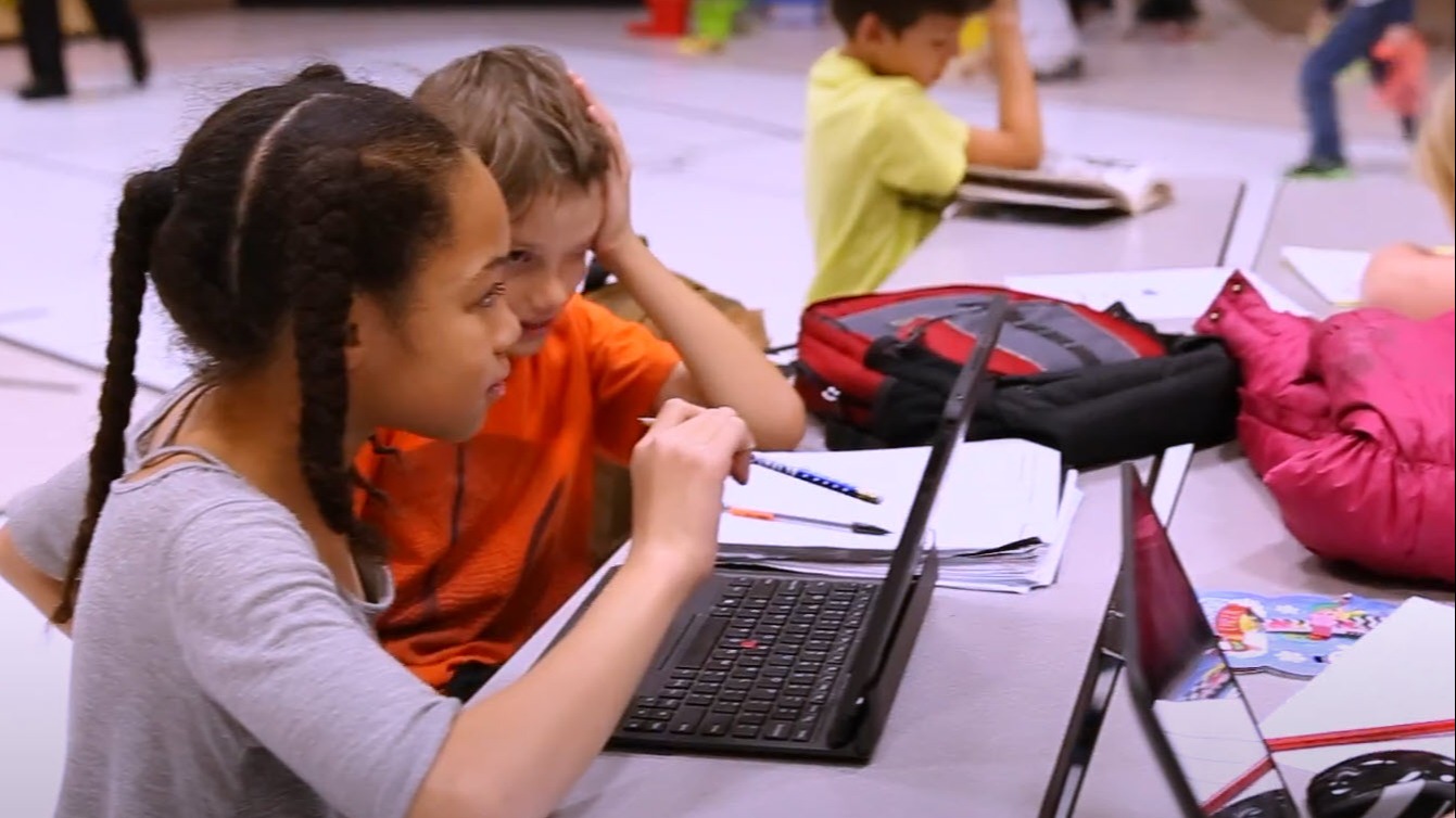 two students looking at a laptop screen