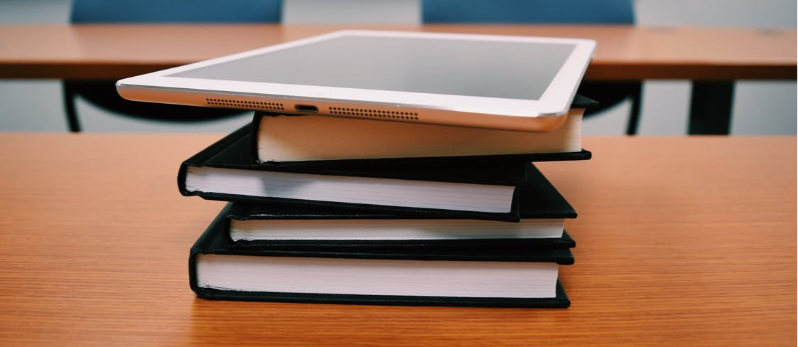 A stack of books with an iPad on top.