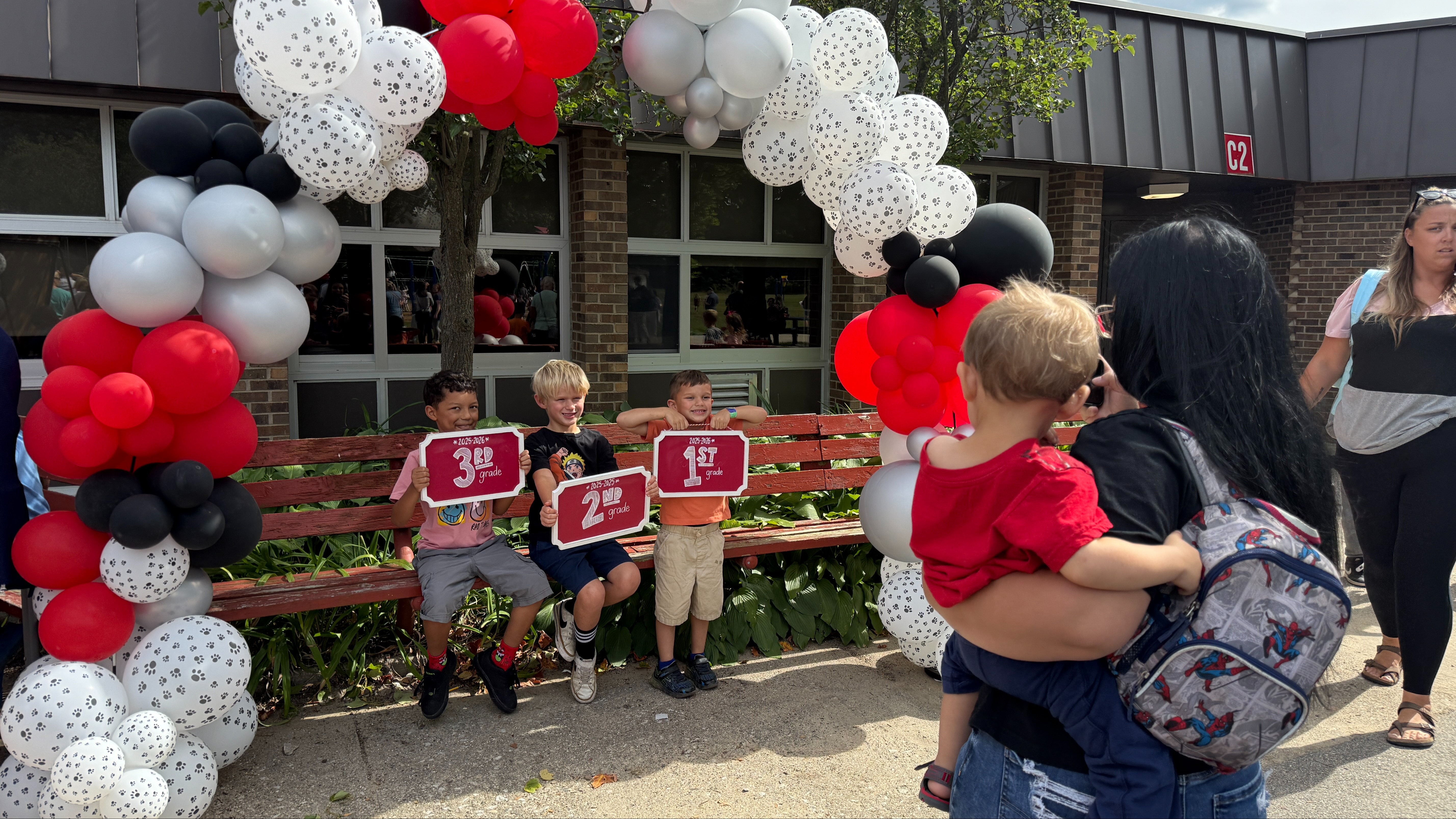 hepto3 young boys posing for a picture under a red & black balloon arch at Highland school  