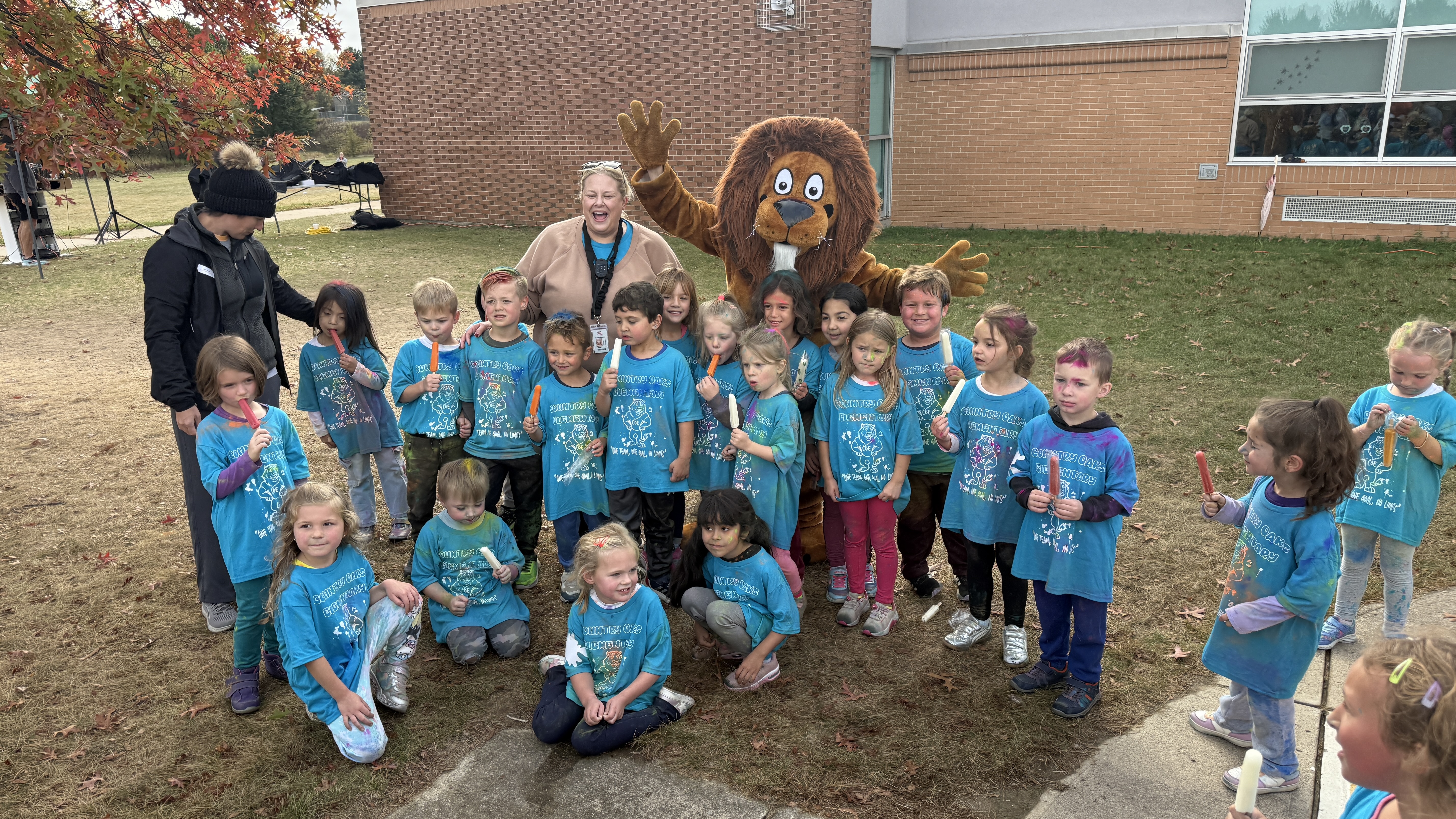 Group photo of kids at Country Oaks Elementary in blue shirts with the Lion mascot celebrating the fun run