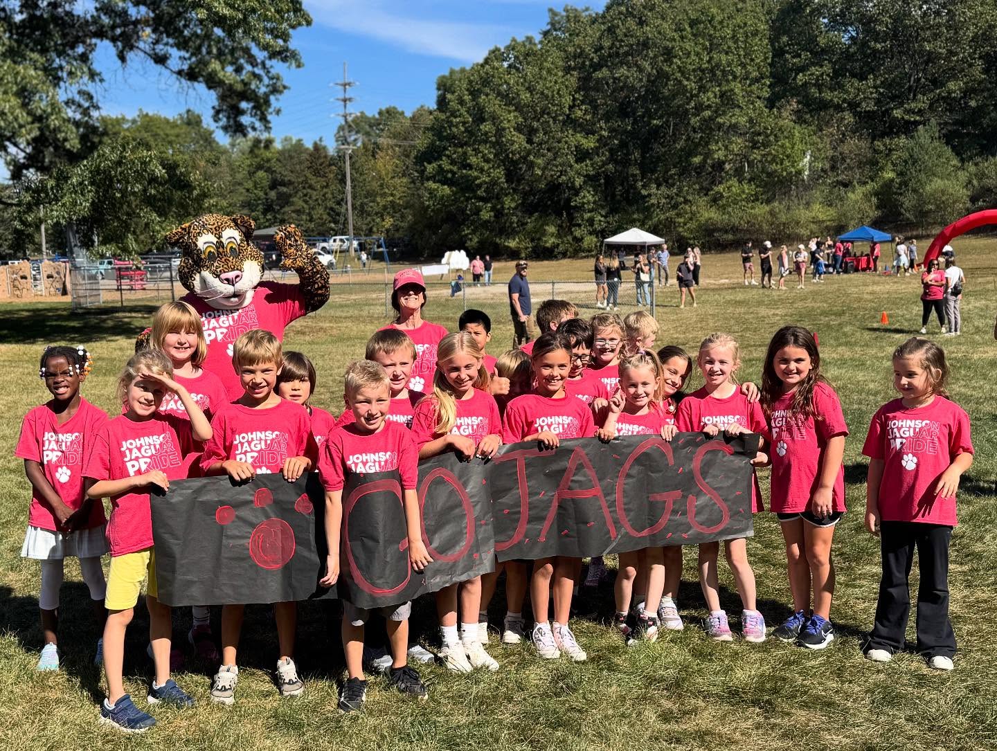 Group photo of students in red shirts outside holding banner that reads "go jags"