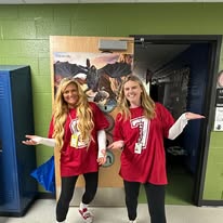 Teachers in matching red shirts pose for photograph inside school