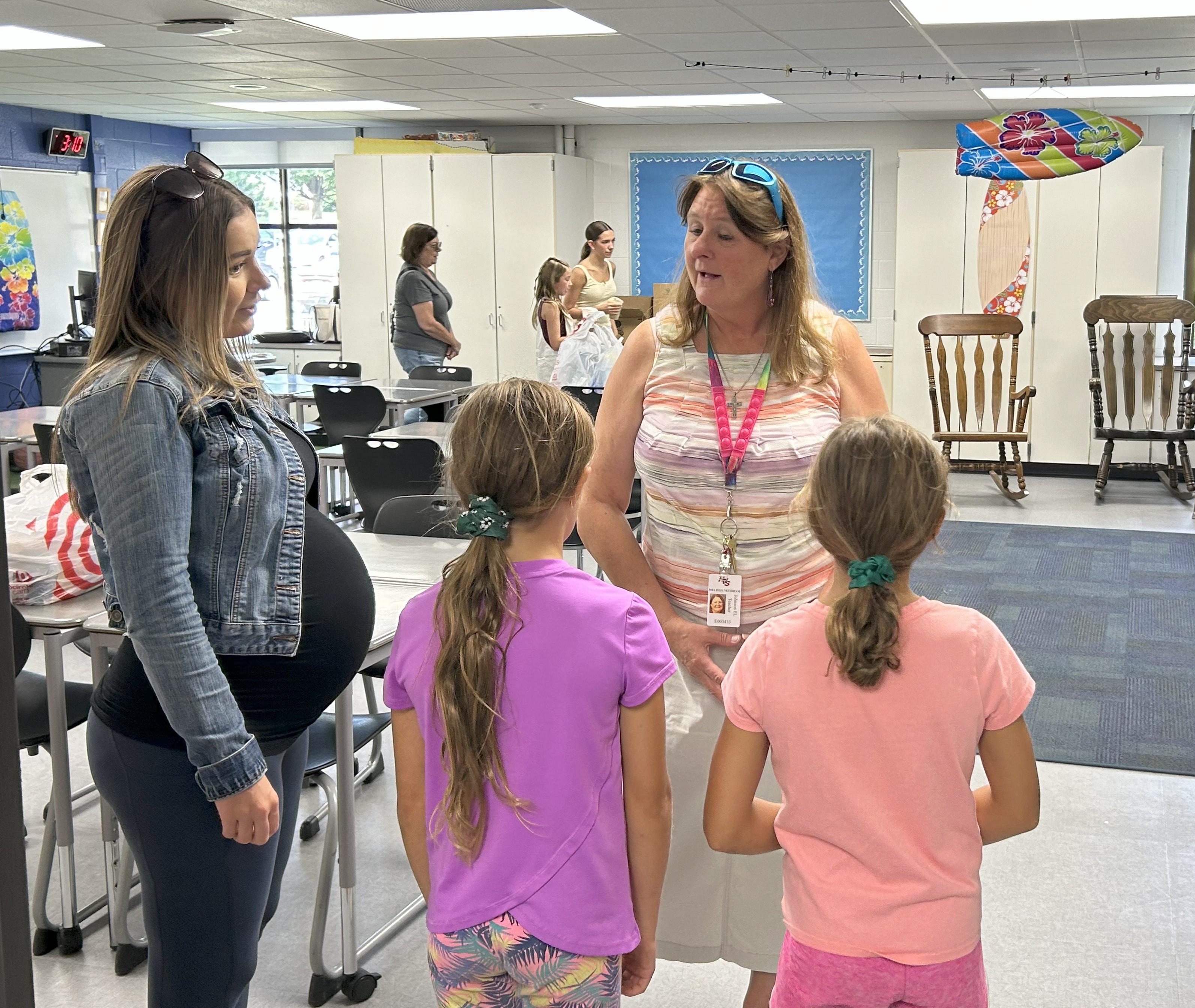 A teacher talkign with a woman and students in a classroom