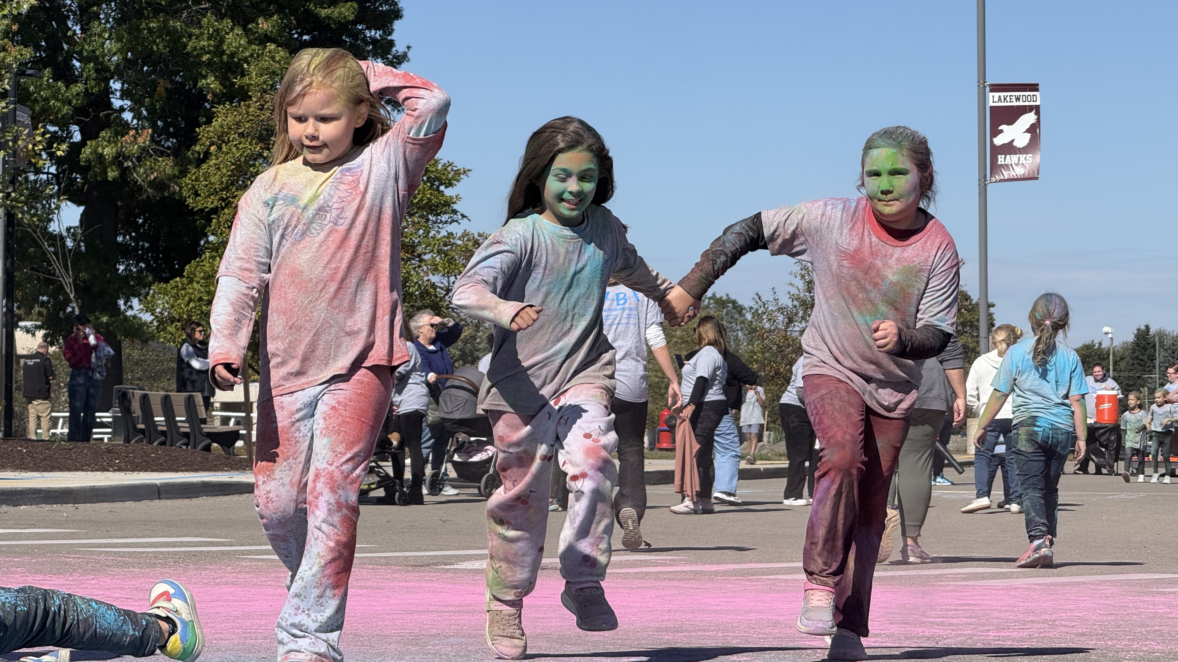Younger students running at color fun run event with shirts a rainbow of colors