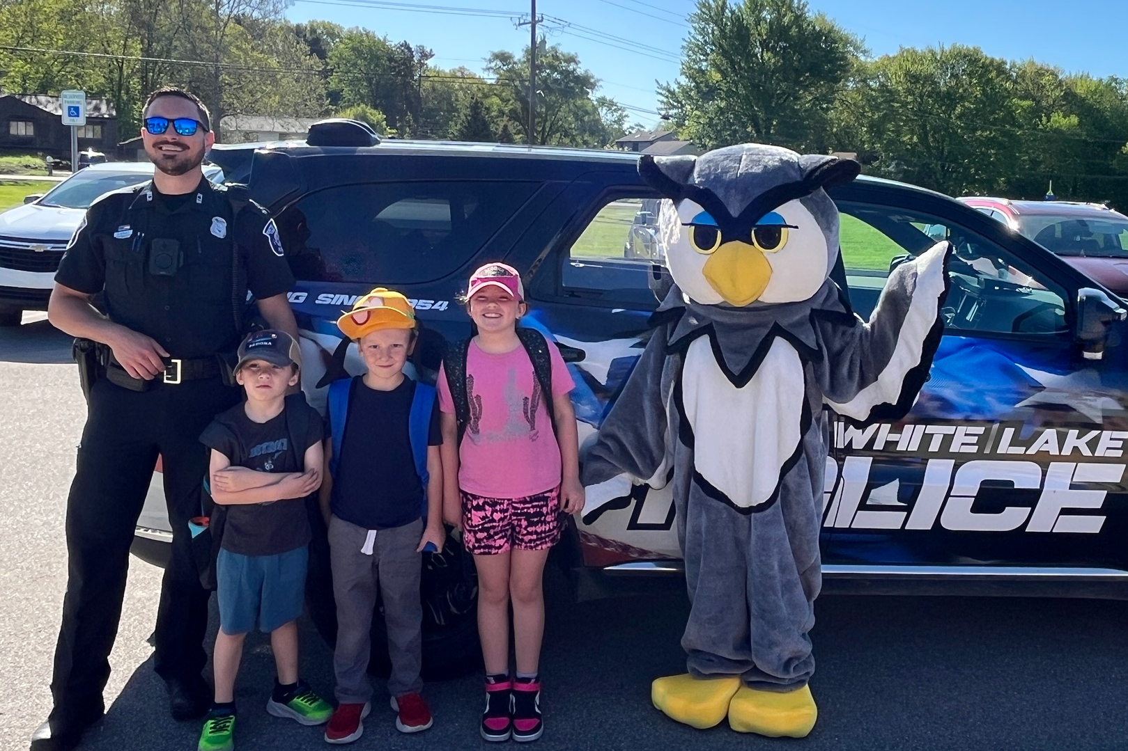 Students with police officer in front of a police car