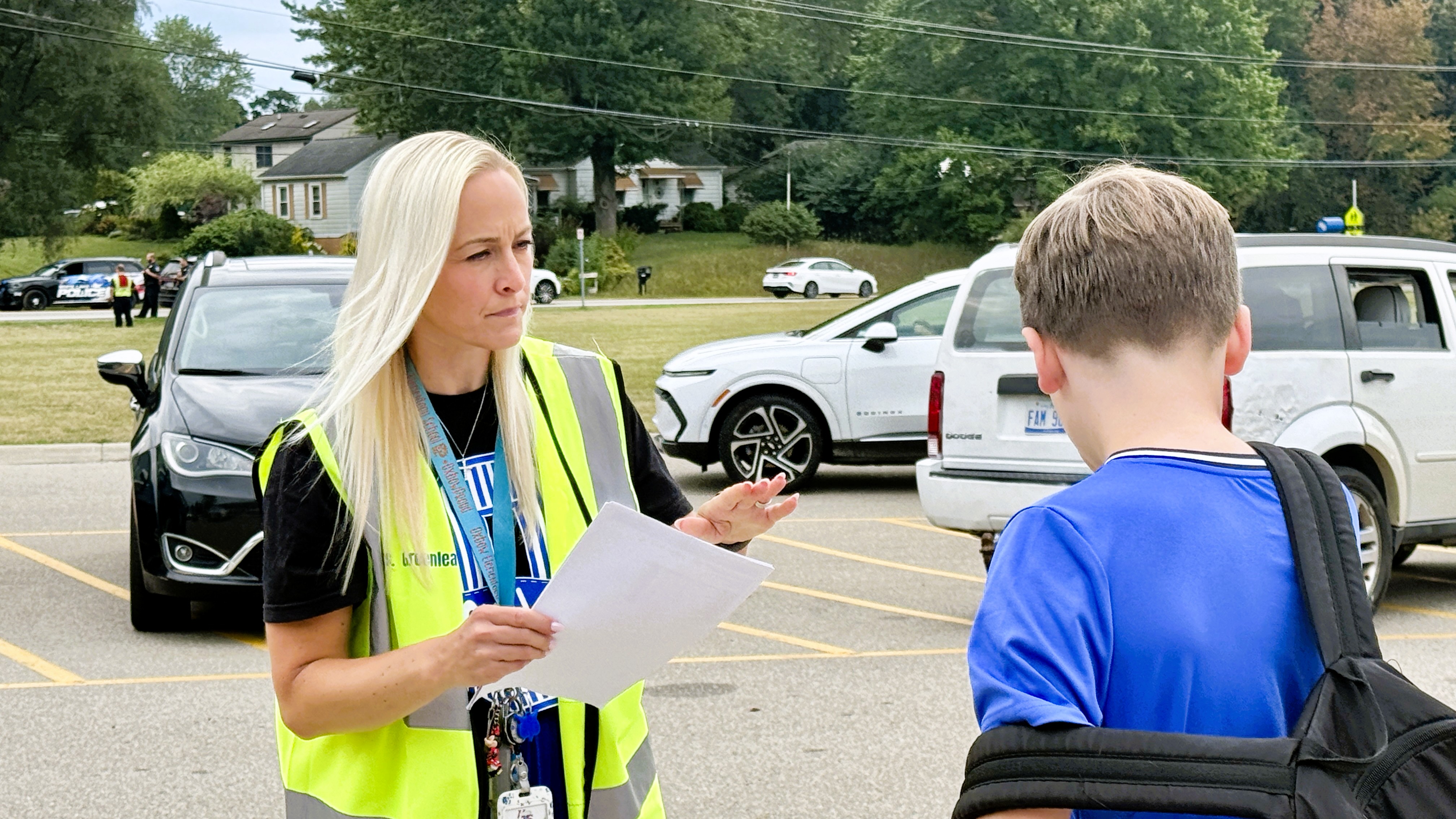 Woman in yellow vest standing outside near a parking lot