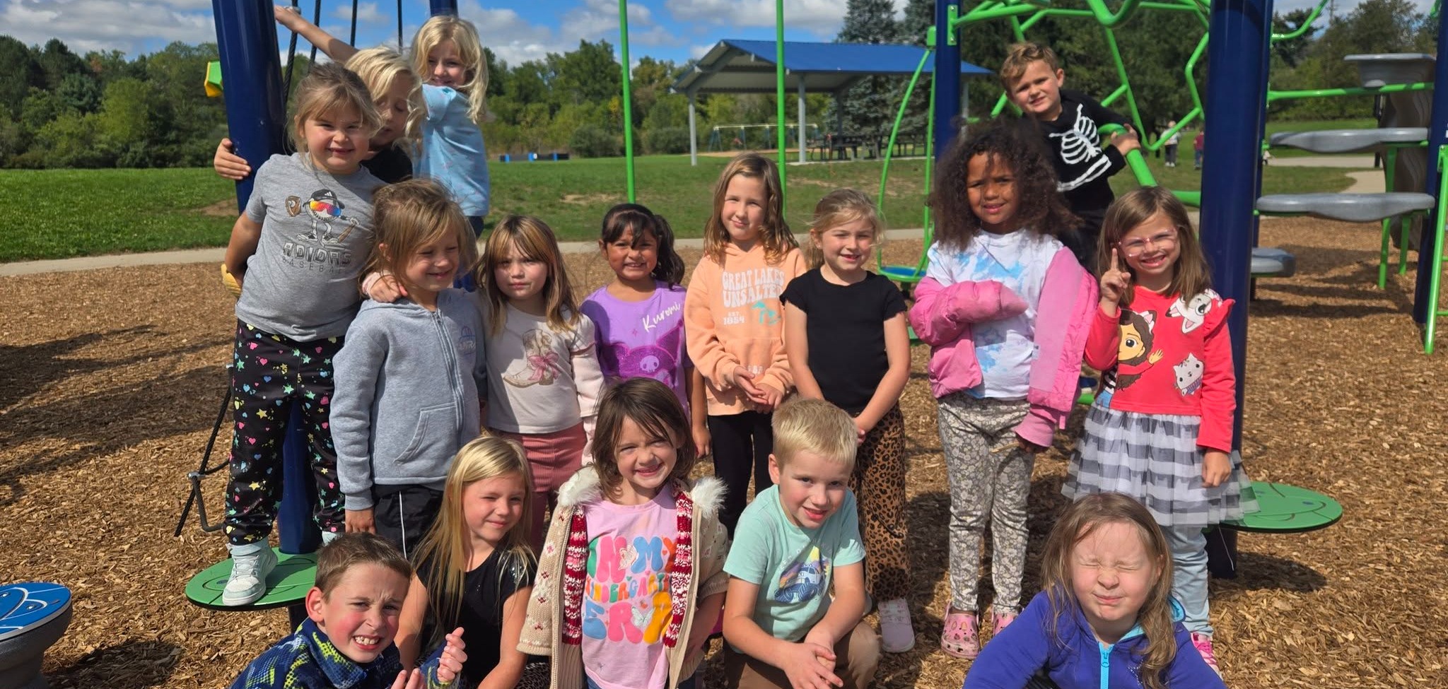 Photo of more than 10 kids  smiling and posing for a picture on a school playground