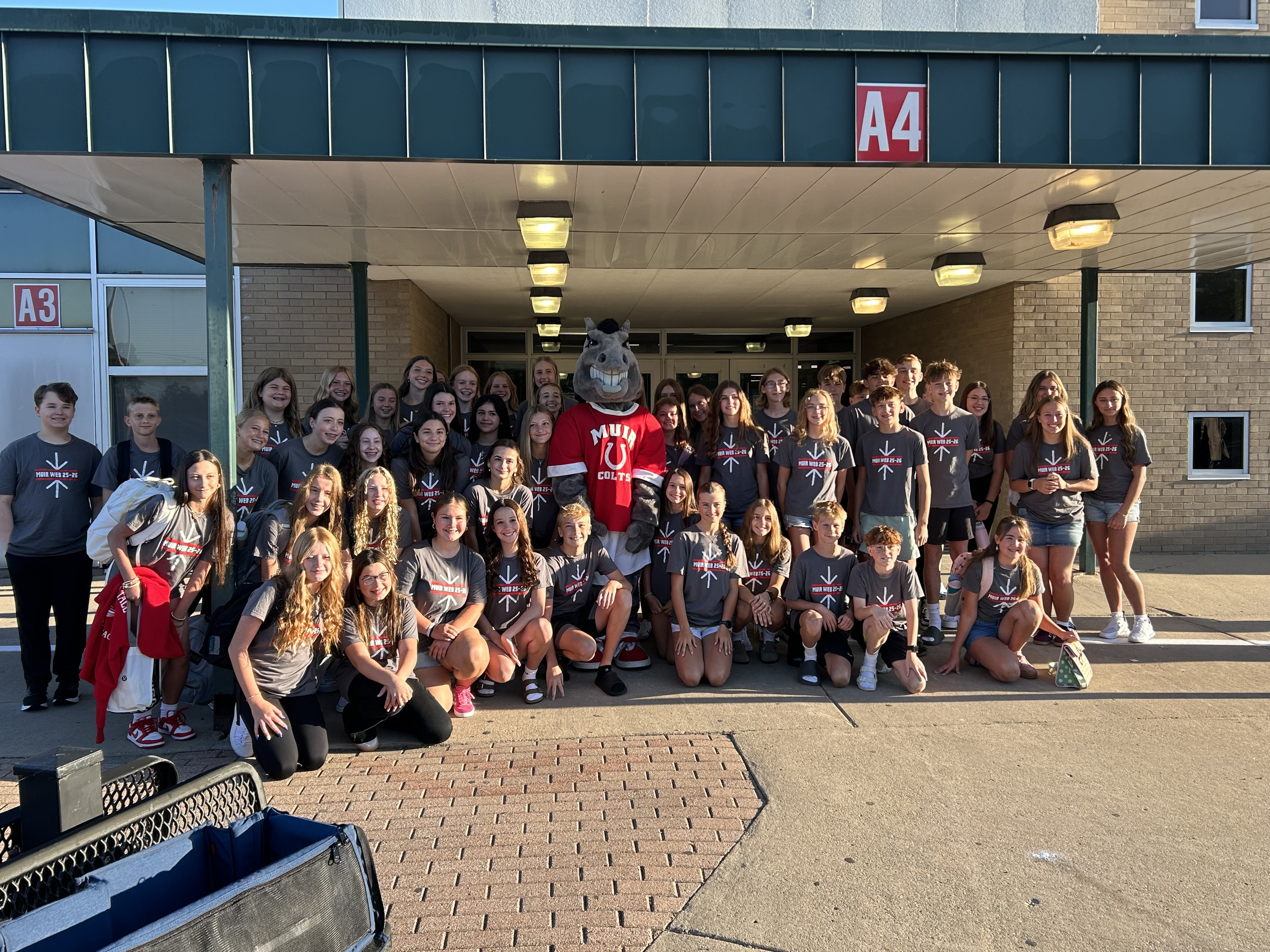 8th grade WEB leaders and the Muir Colt mascot welcome back students.