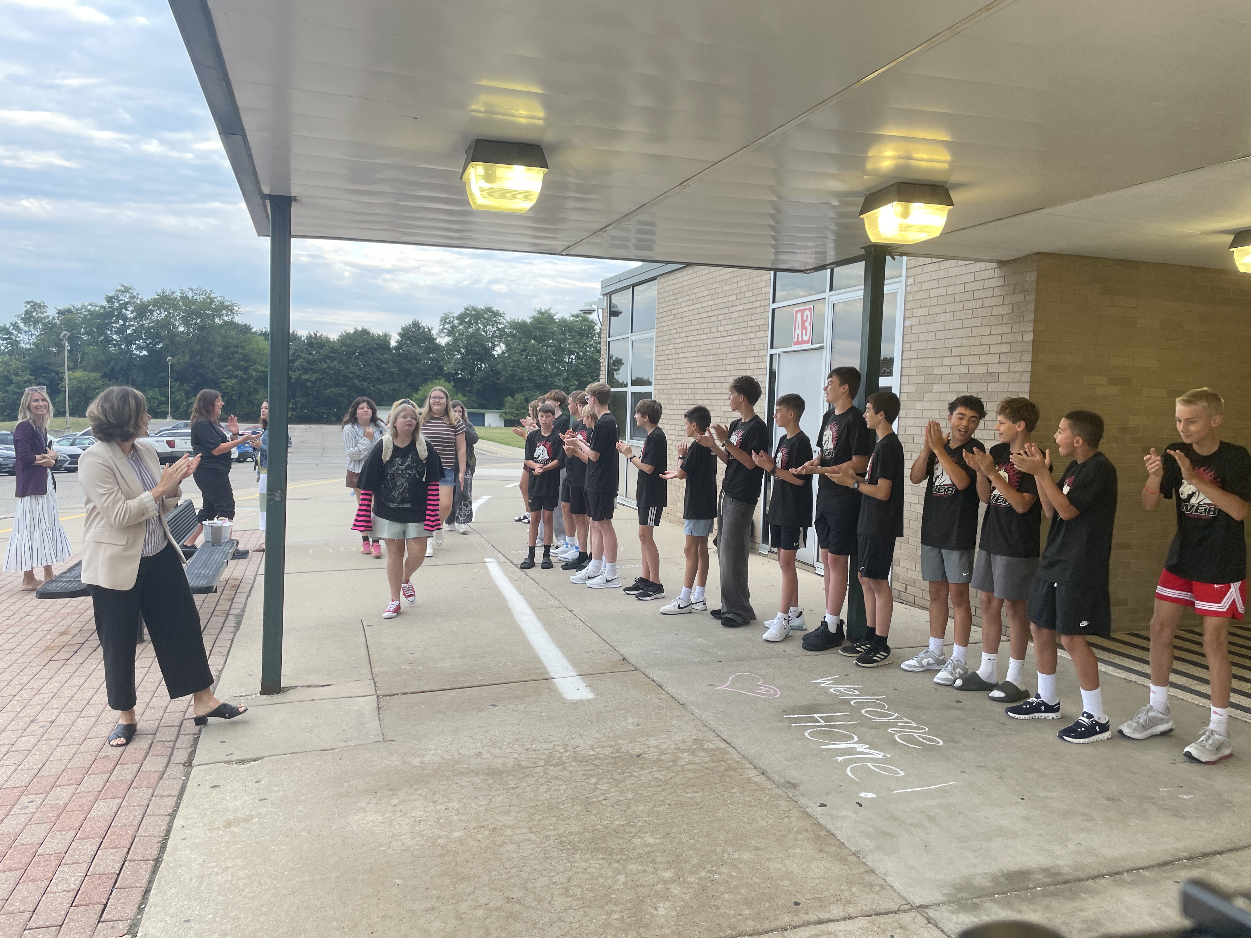students waling into school through the front door as other kids clap