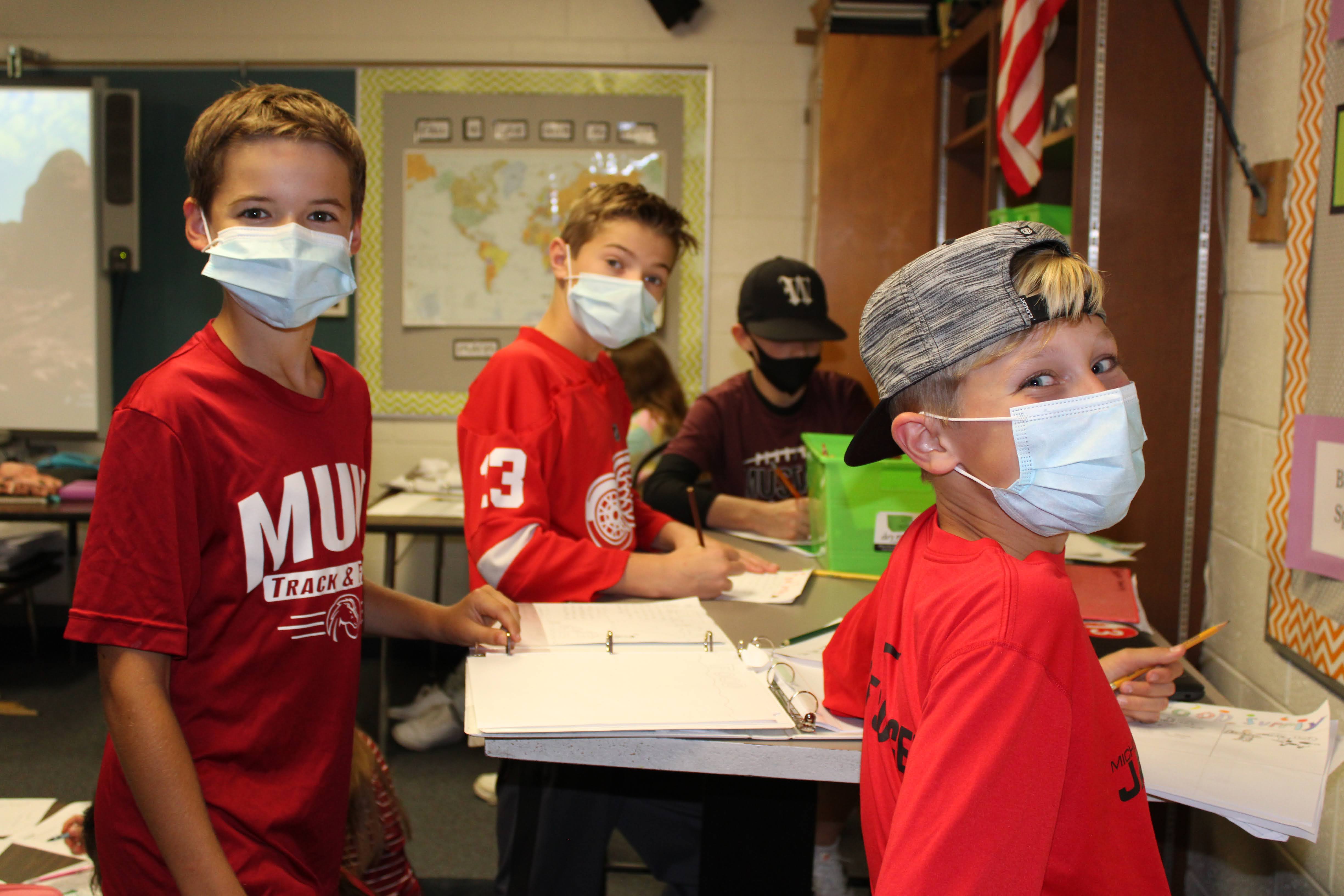 Students wearing red Muir Spirit Wear smile in class.