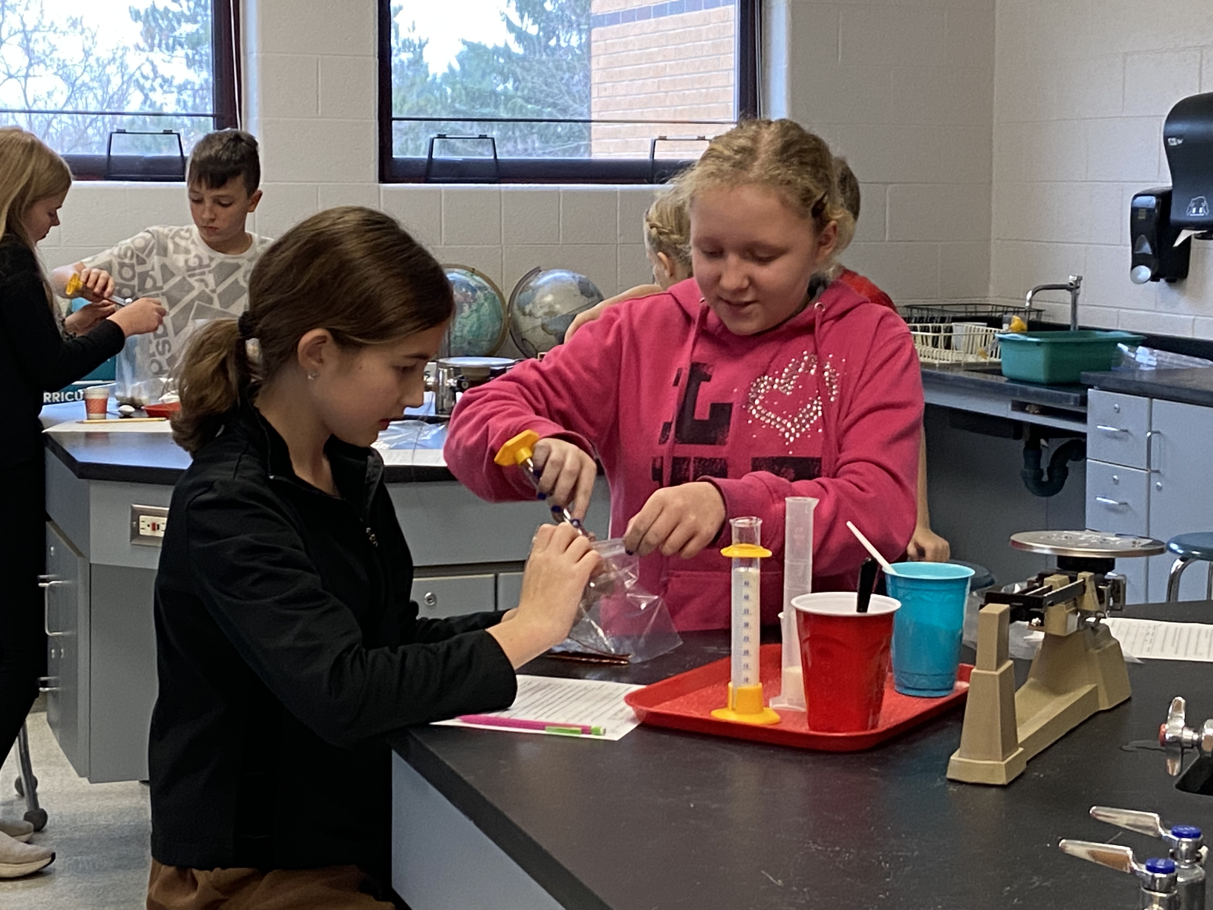 girls pouring salt in science lab