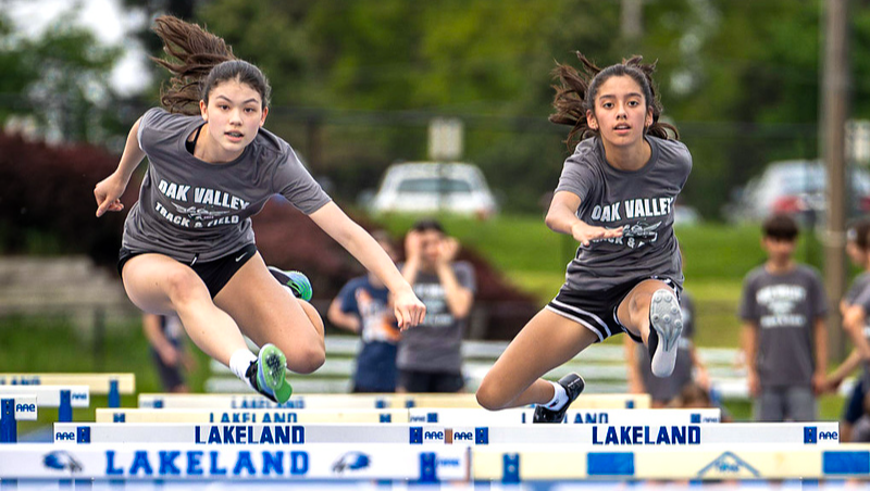 two girls jumping hurdles