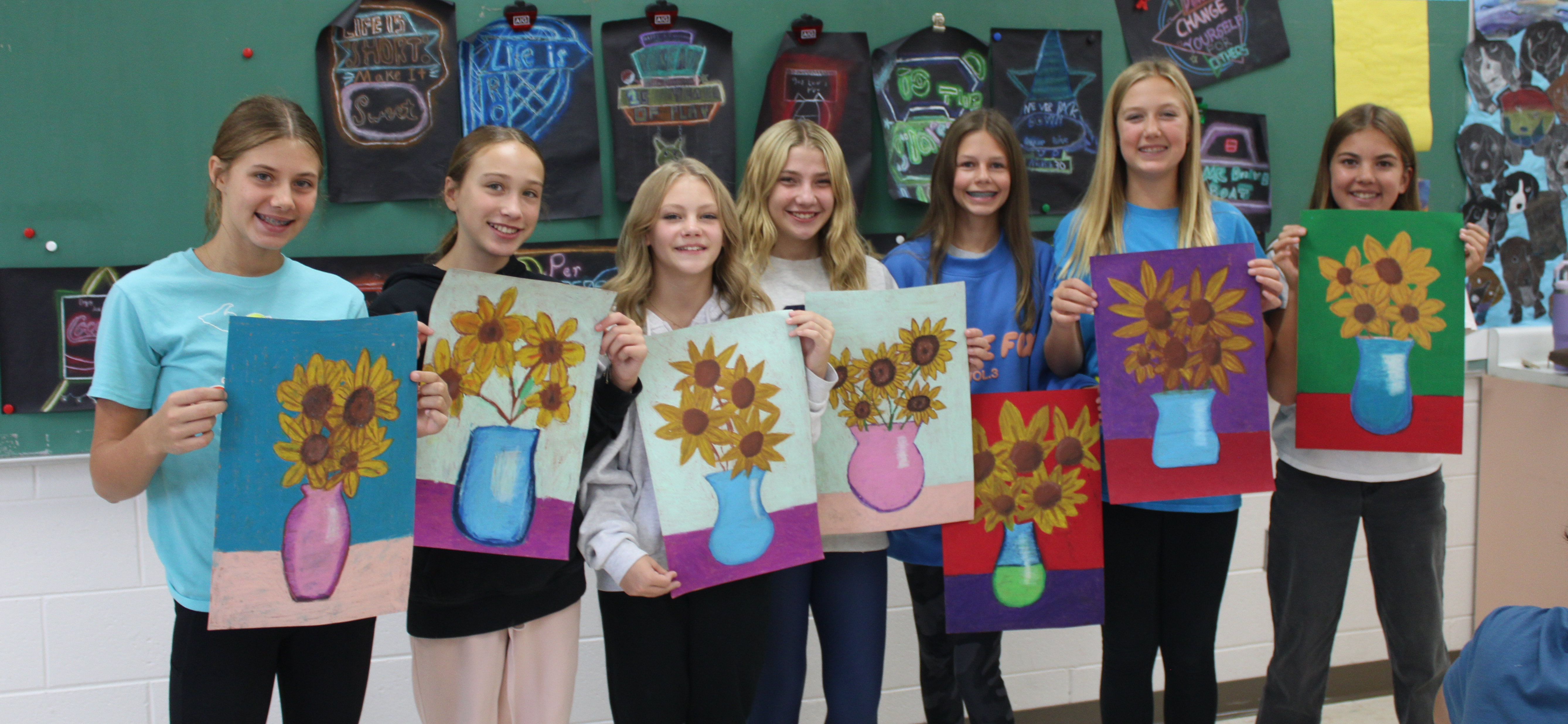 girls showing sunflower drawings
