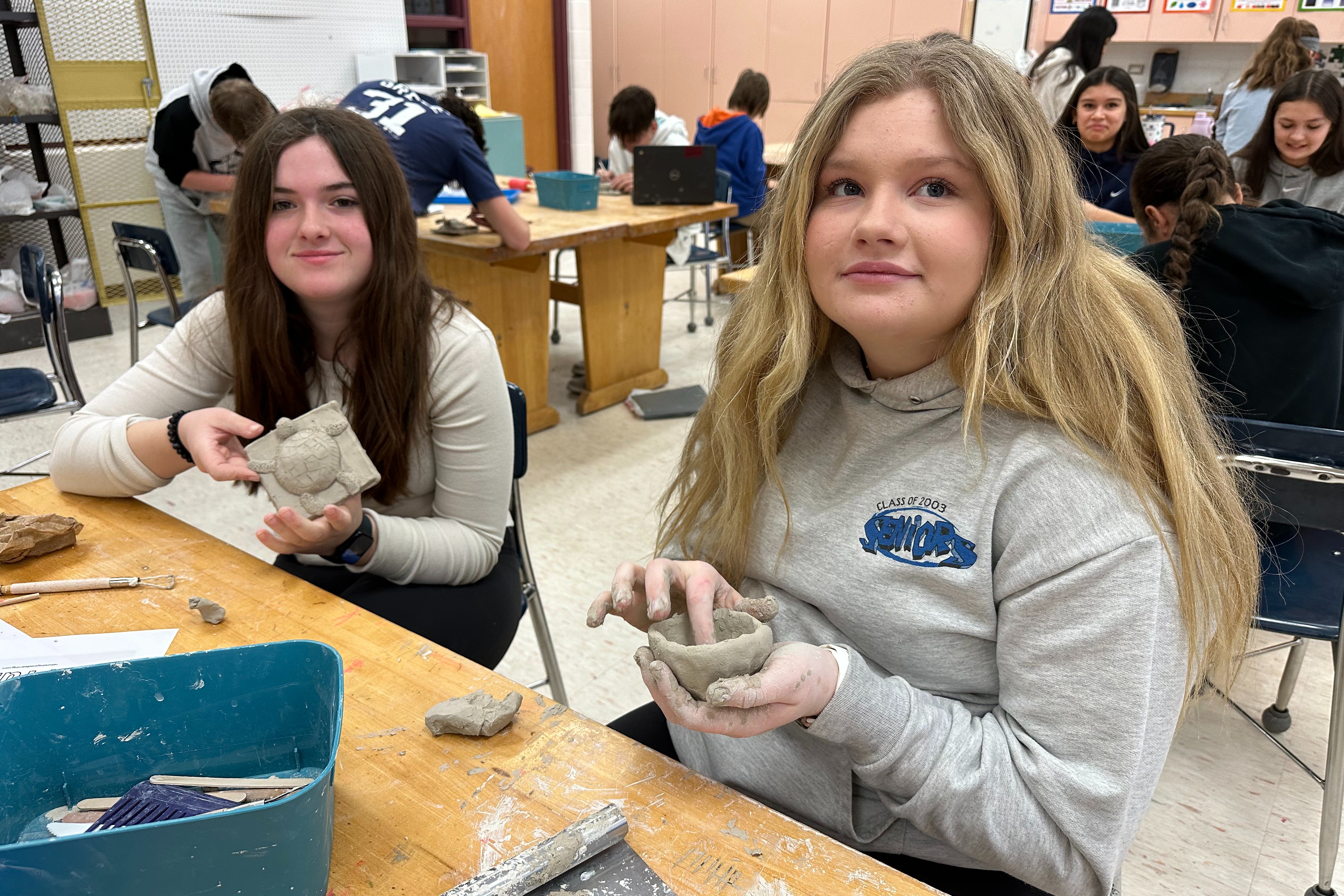 two girls forming sculptures with clay