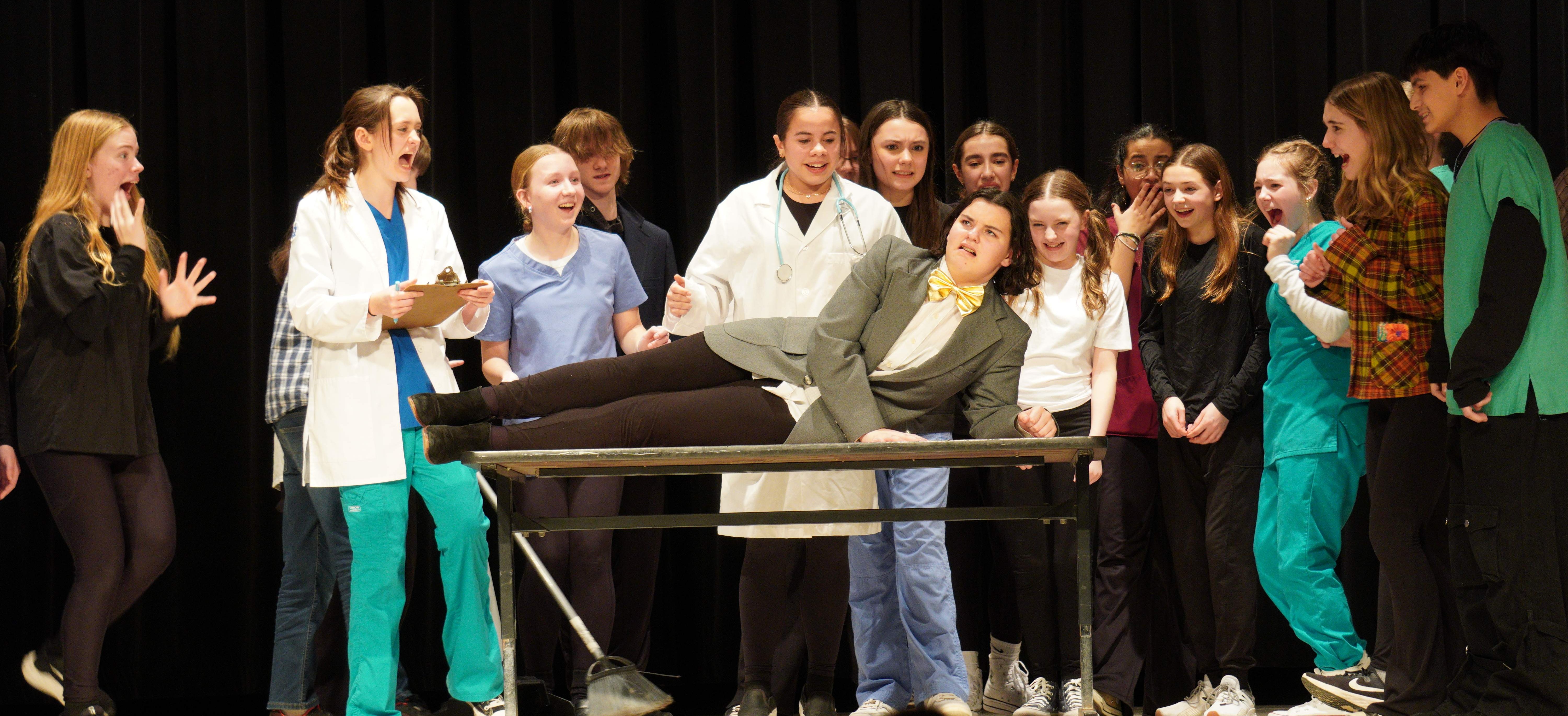 students gather around a patient in a play