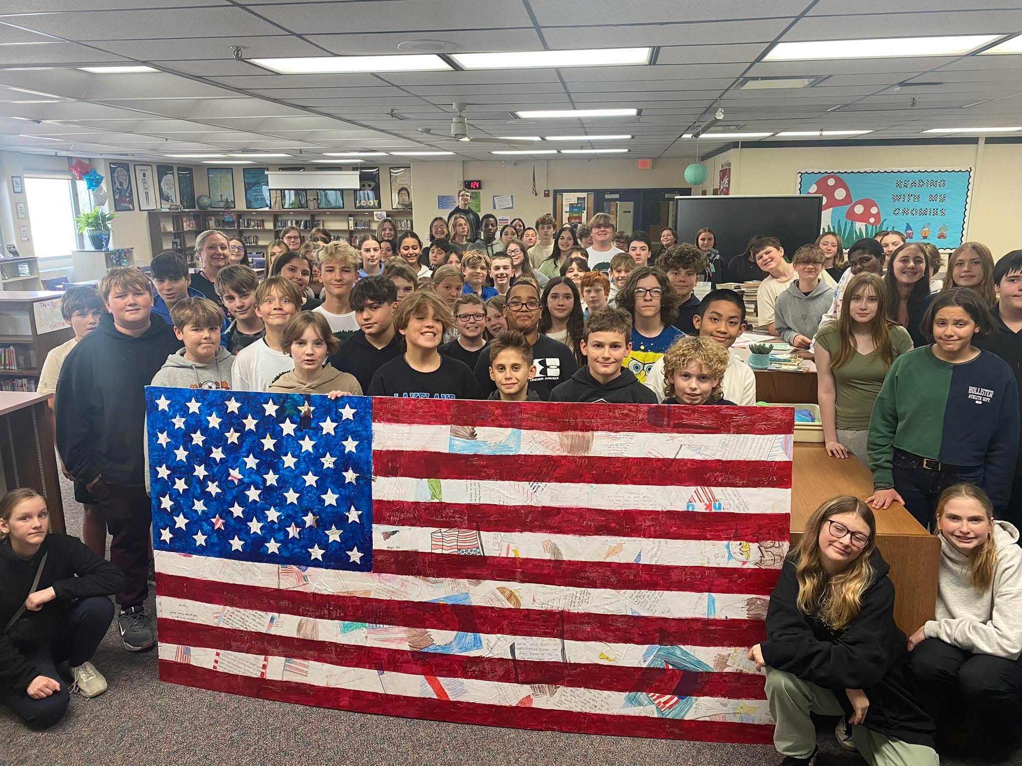 WLMS Art classes pose with their collaborative art piece for Veteran's Day