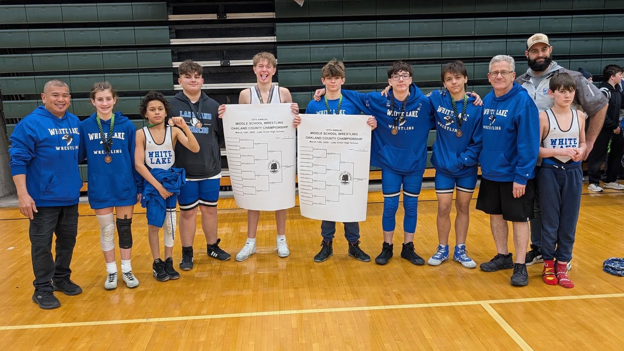 Wrestling team holding bracket sheets for two different division