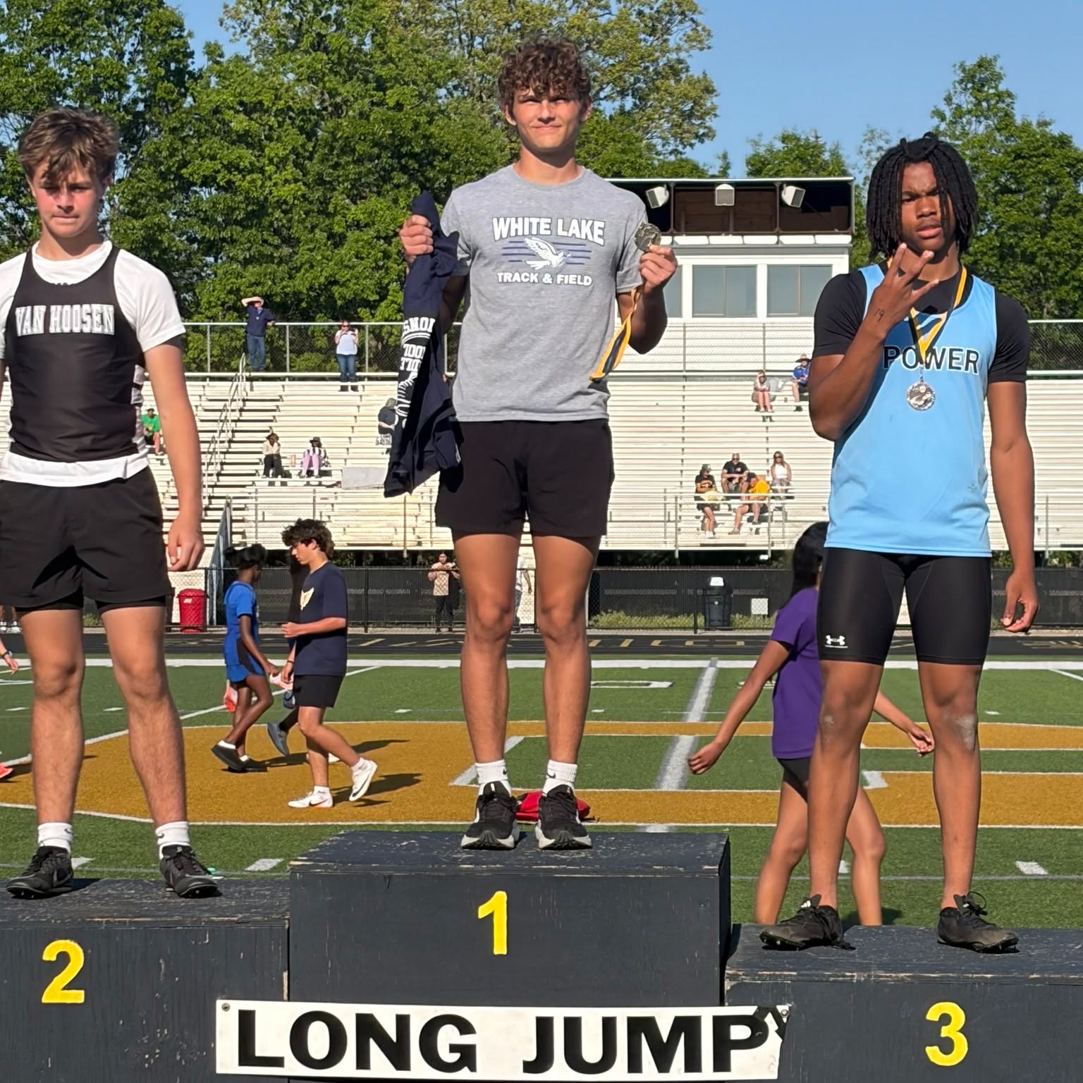 runner posing for a photo with medals around their neck standing on podium 