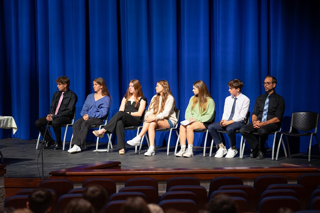 Seven people sitting on a stage 