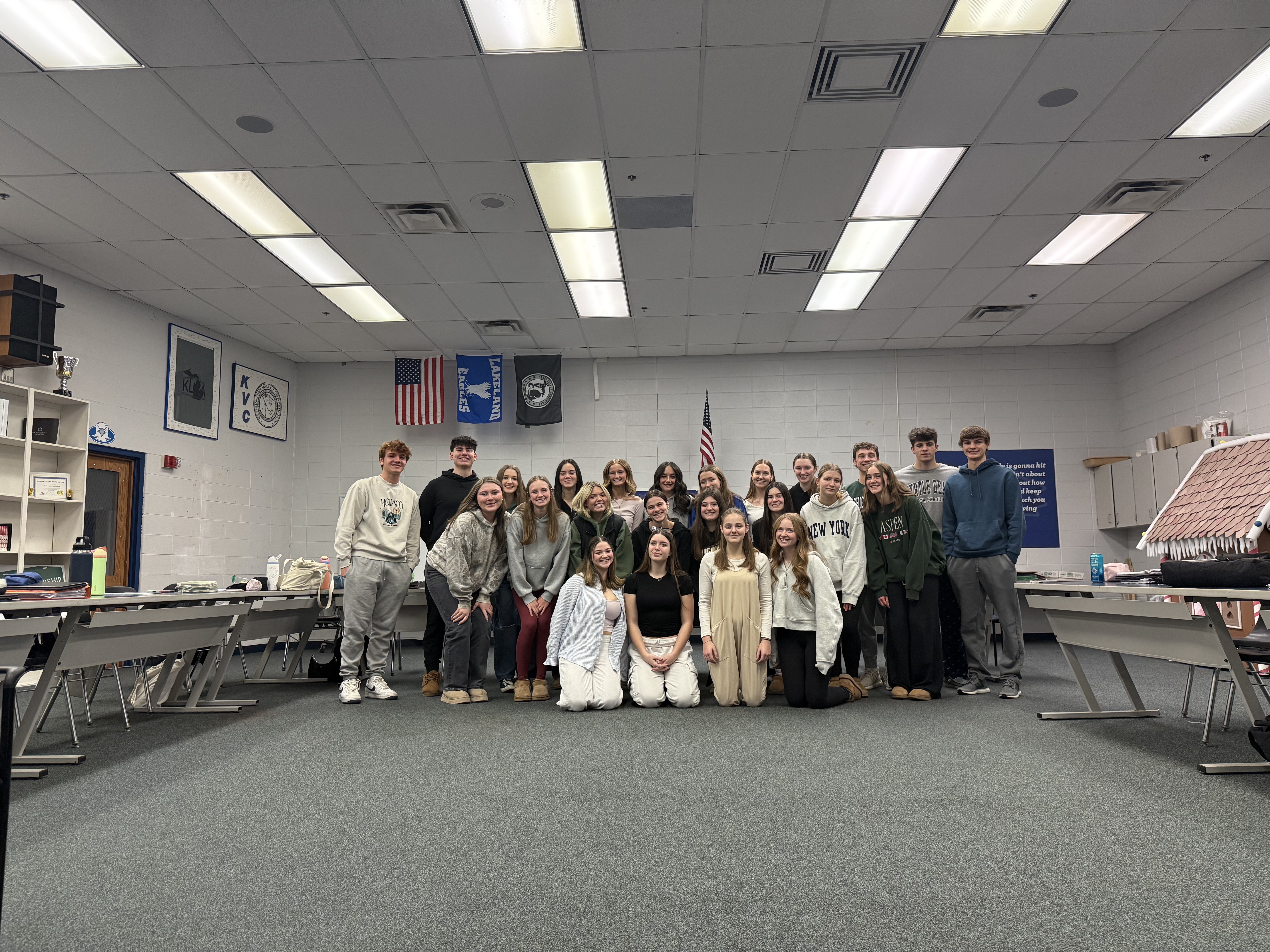 A group of high school students standing in a classroom. 