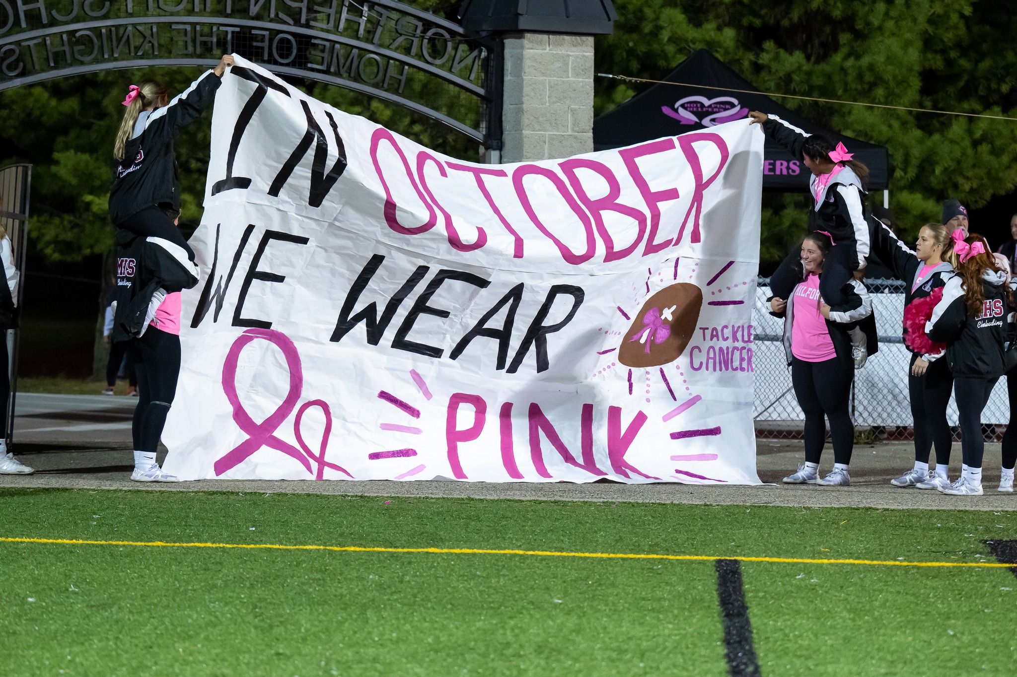 cheerleaders hold sign at mhs football game.
