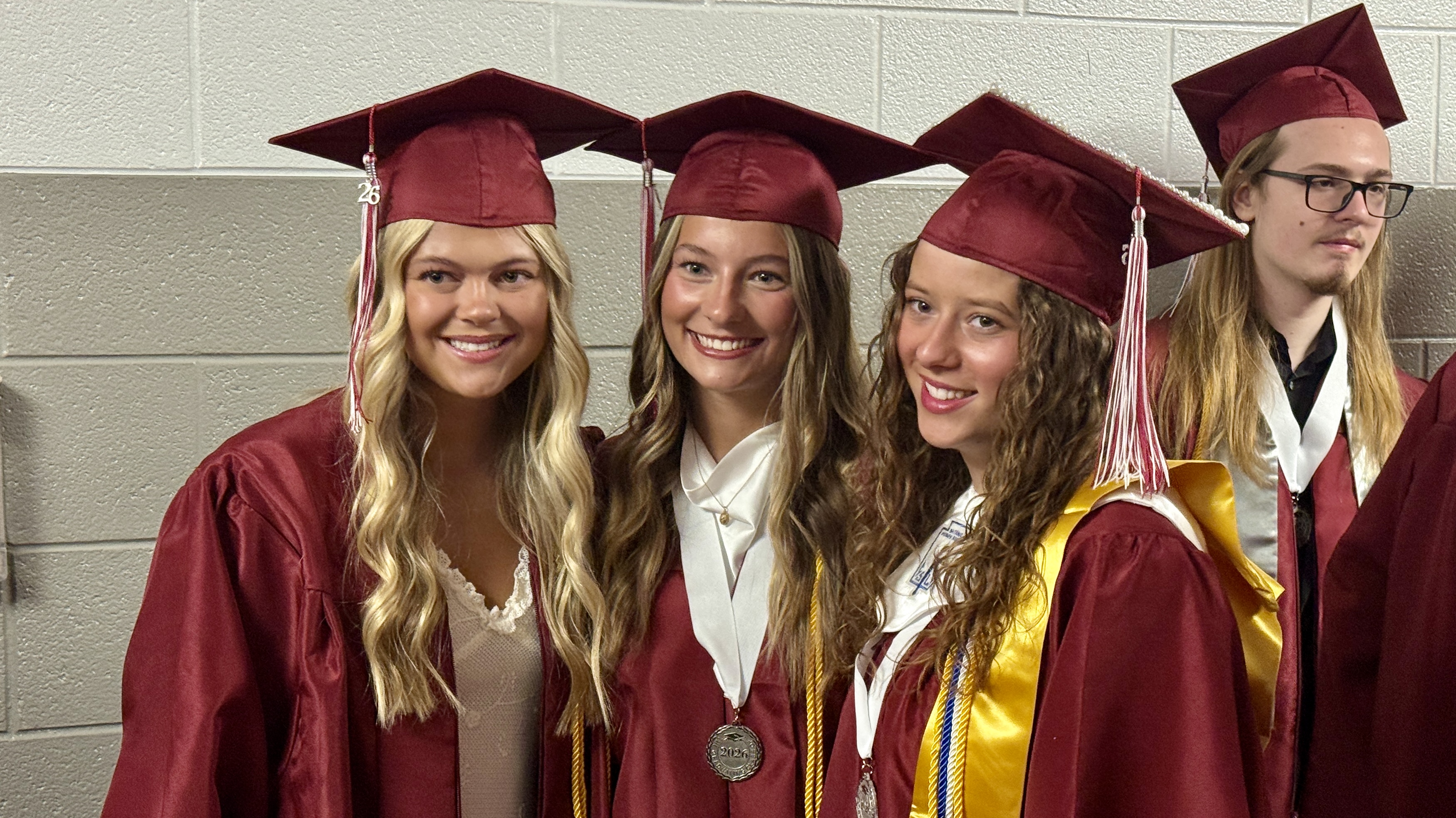 students in cap & gown posing for photo at graduation ceremony