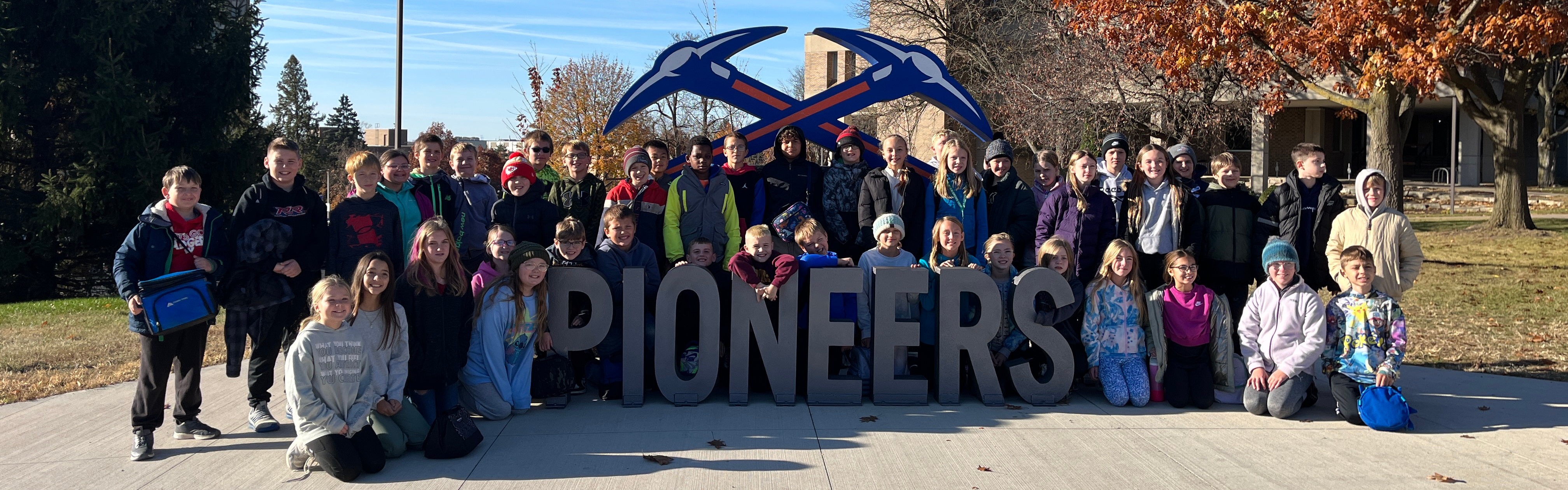 students take a picture by the pioneer sign