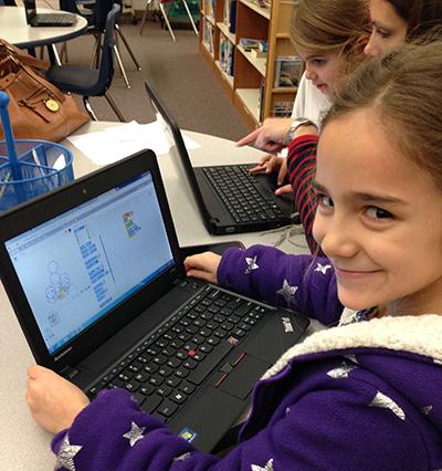 A smiling girl using a laptop