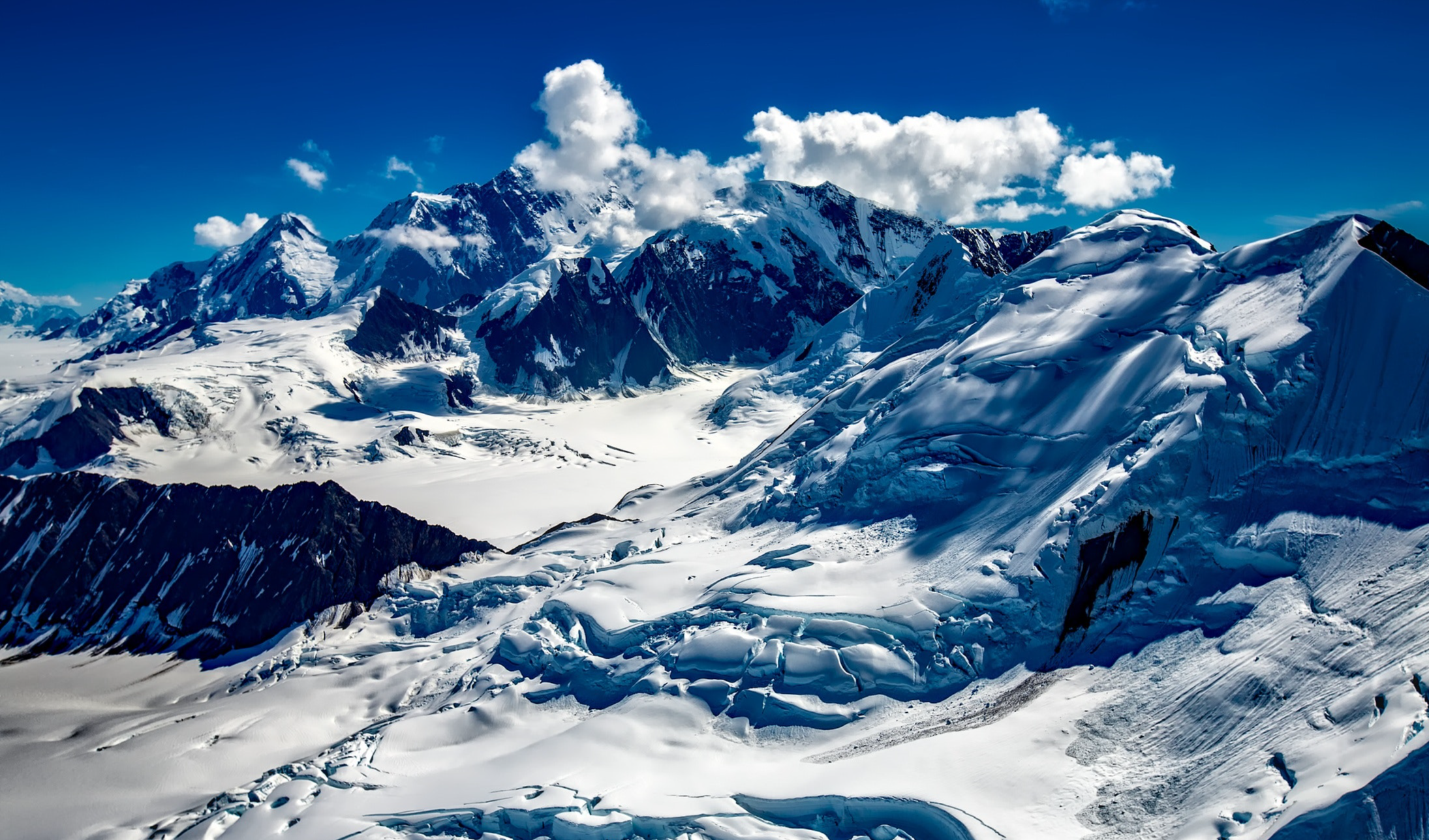 vibrant image of snow covered mountains with bright blue sky