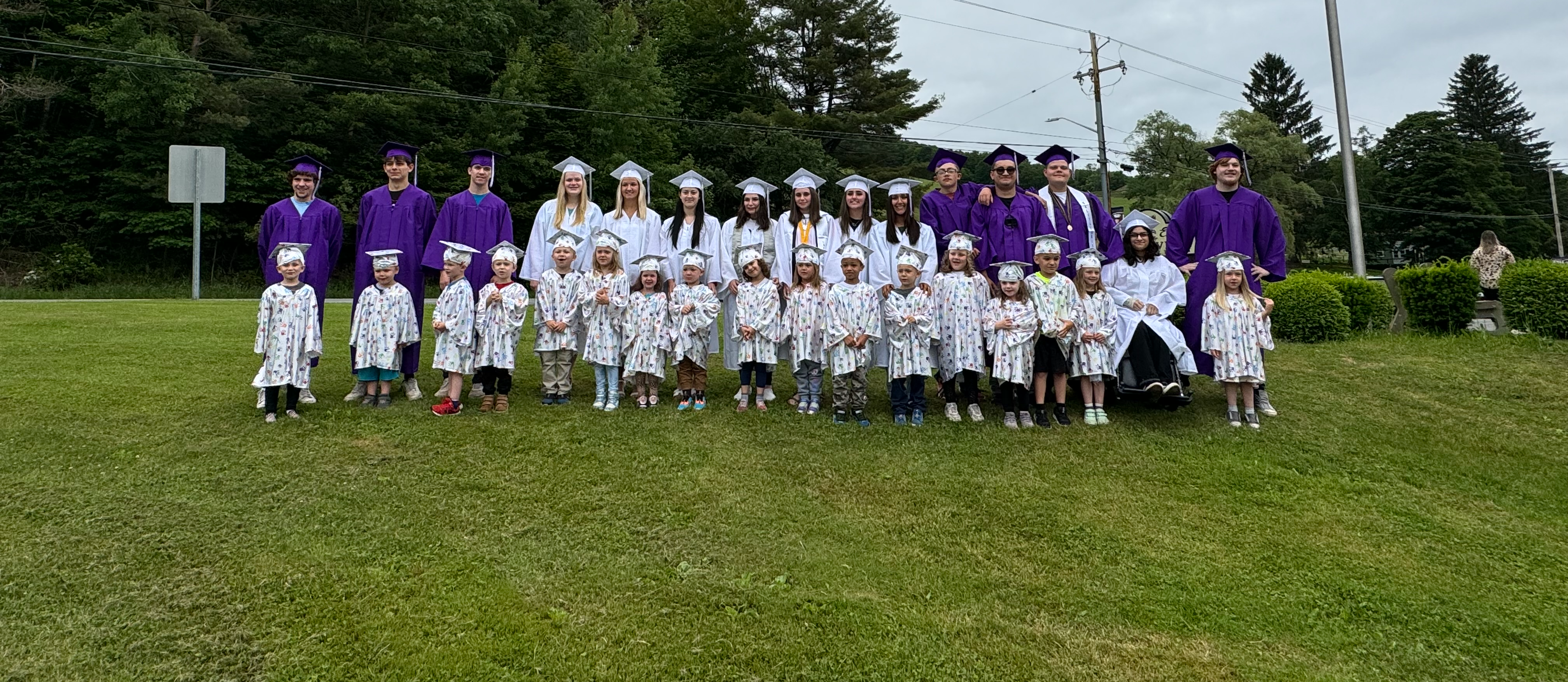 seniors and prek kids standing with cap and gowns