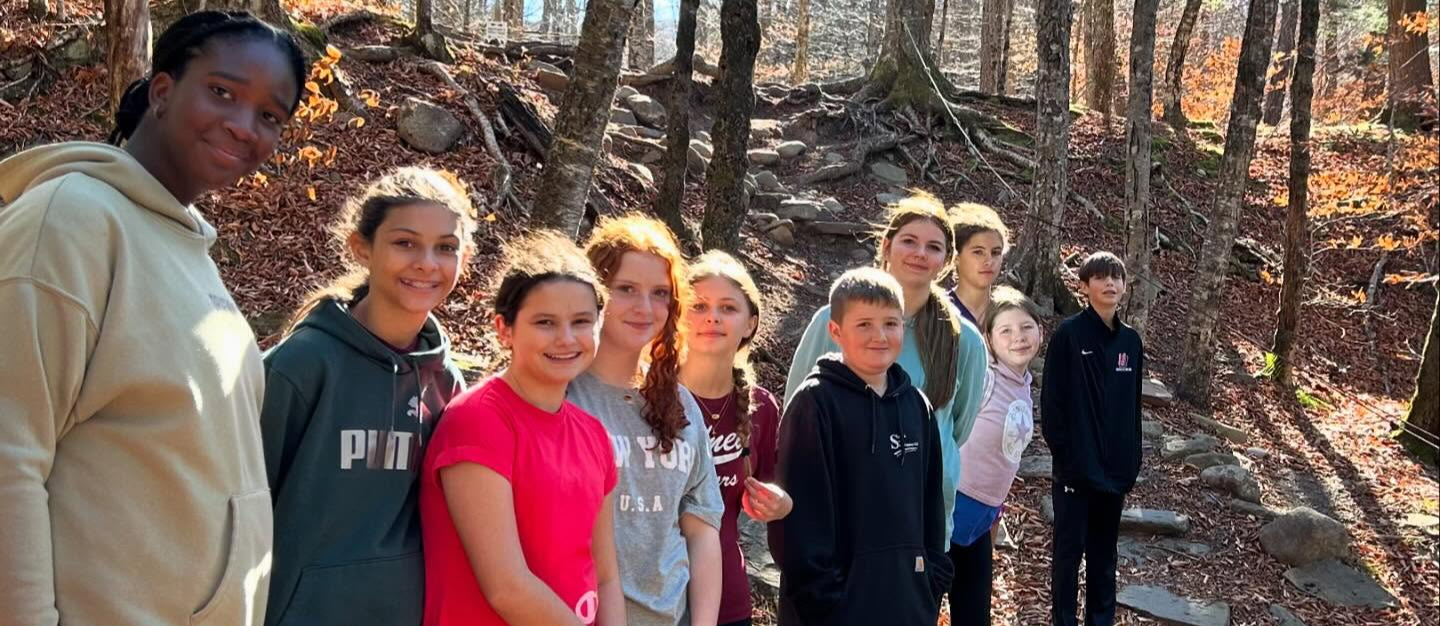 students standing in woods on wooden bridge