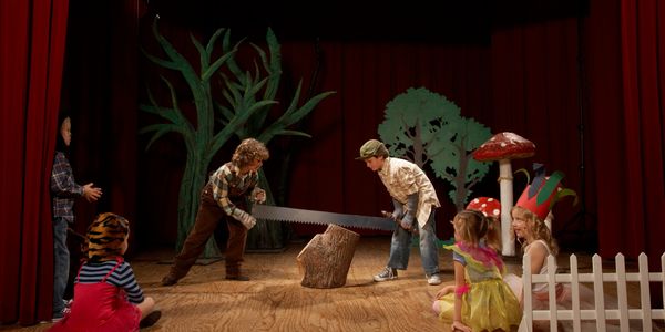 Scene from a school play with two boys sawing a piece of wood