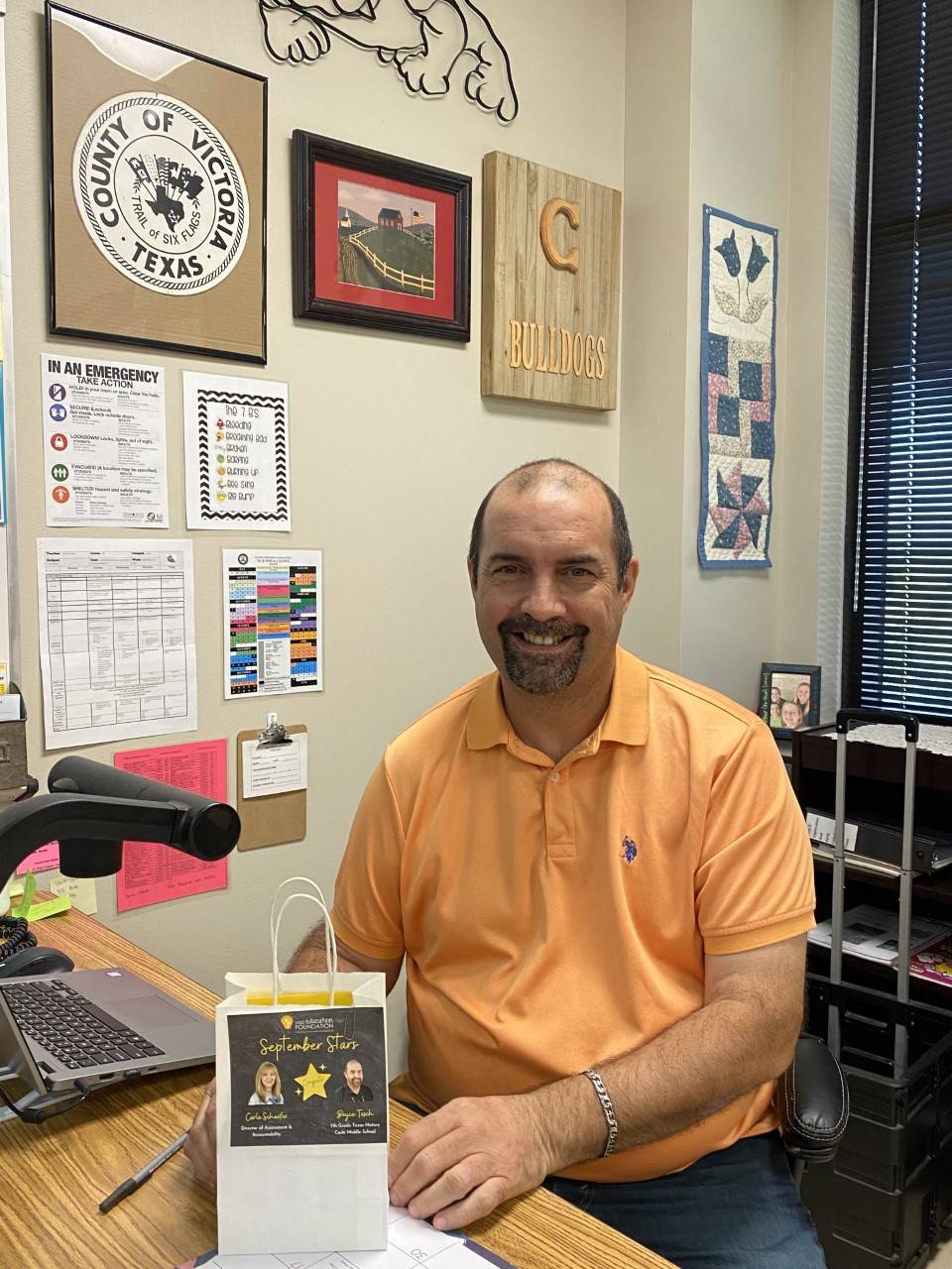 Teacher holding a gift bag and smiling at the camera