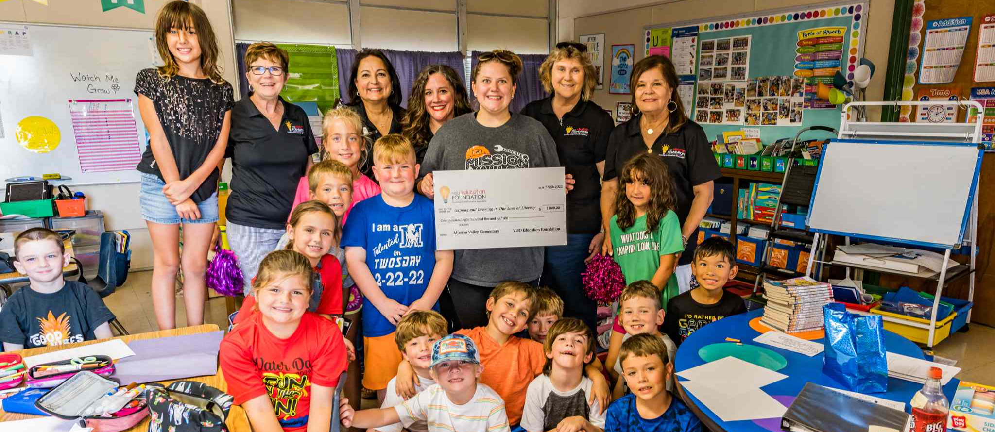 Classroom of students smiles with check from grant