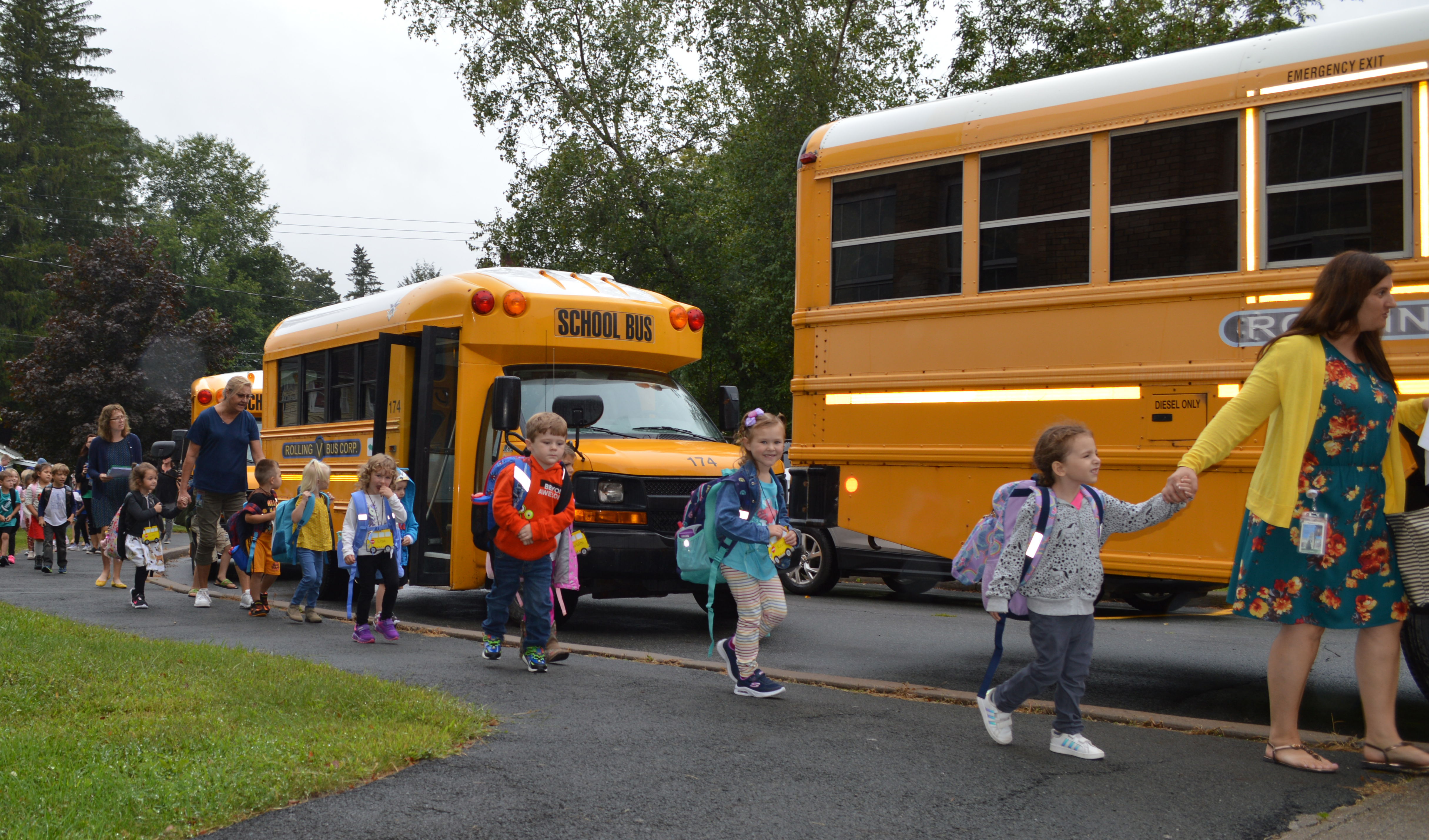 students walk in a line to board school buses