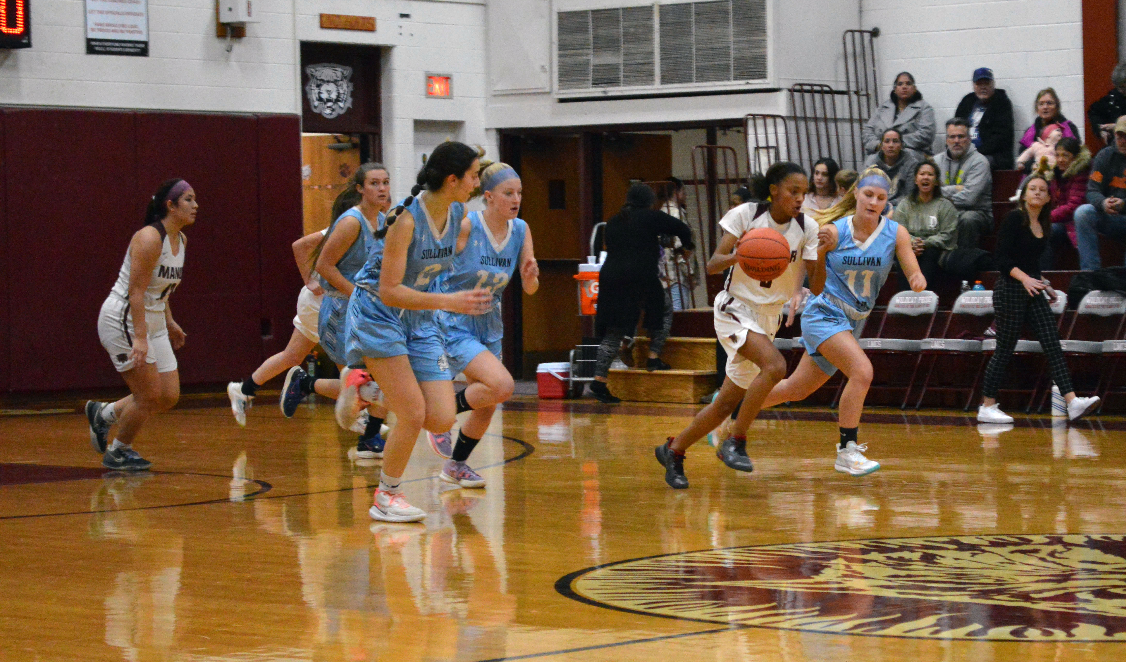 A Manor player dribbles down the court  as SW players pursue during a girls basketball game