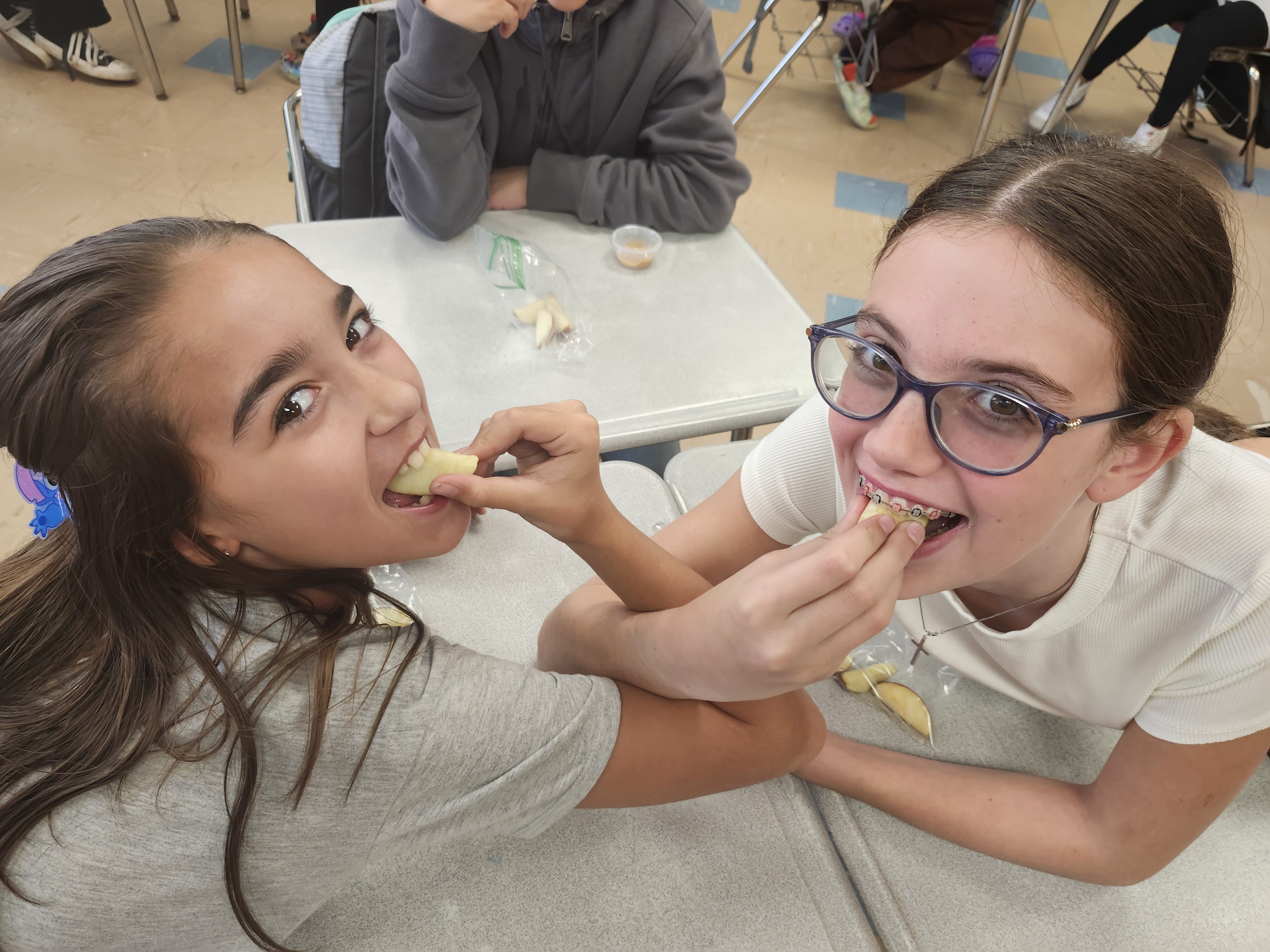 Two students interlock arms to eat apples