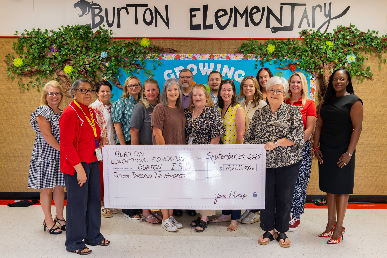 Group of smiling adults holding an oversized check