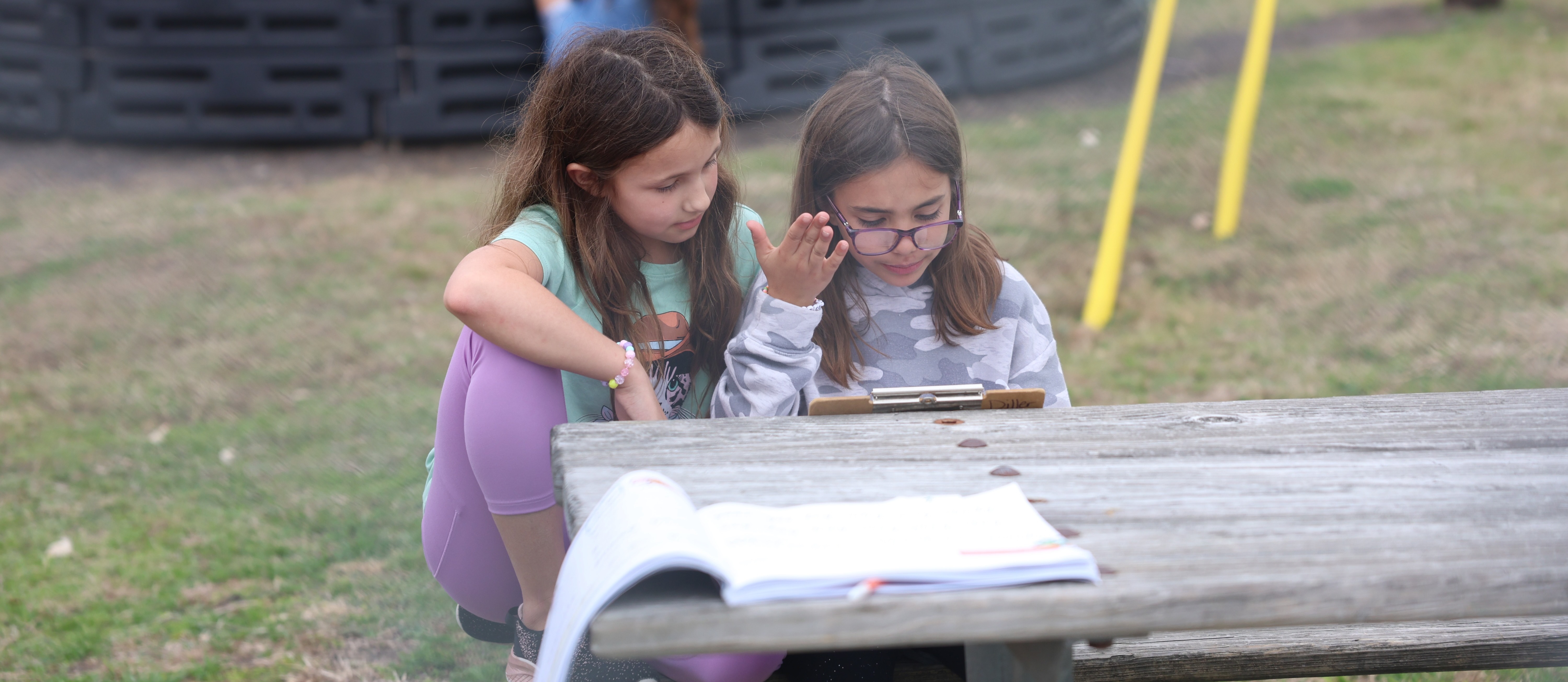 2 girls sitting at picnic table 