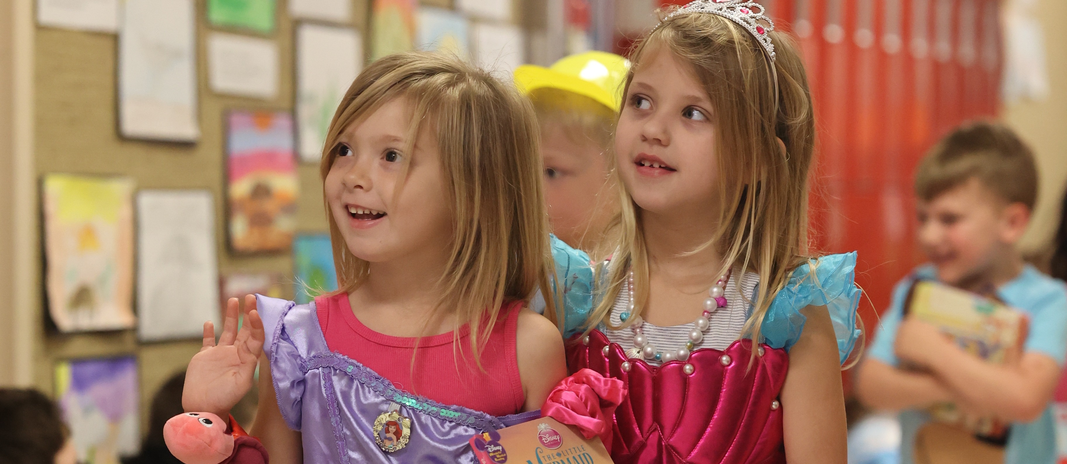 2 girls dressed as mermaids holding a book