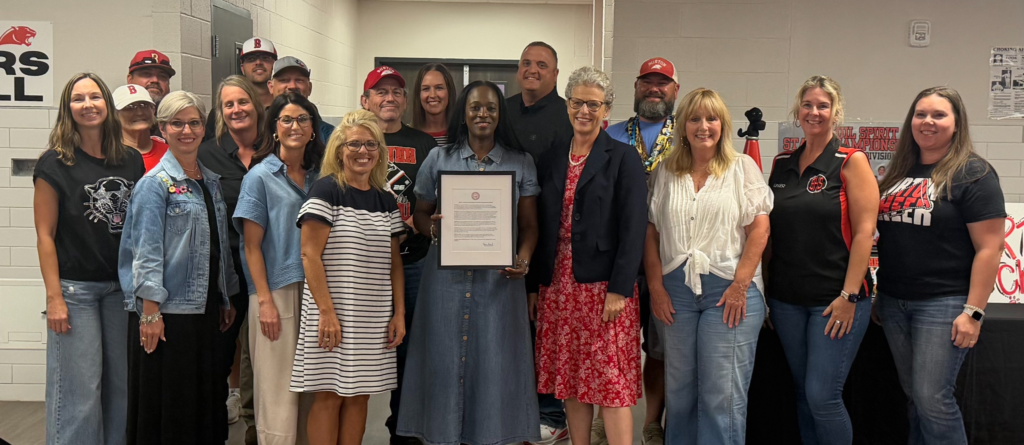 Group of Adults standing and smiling around a central woman holding an official proclamation